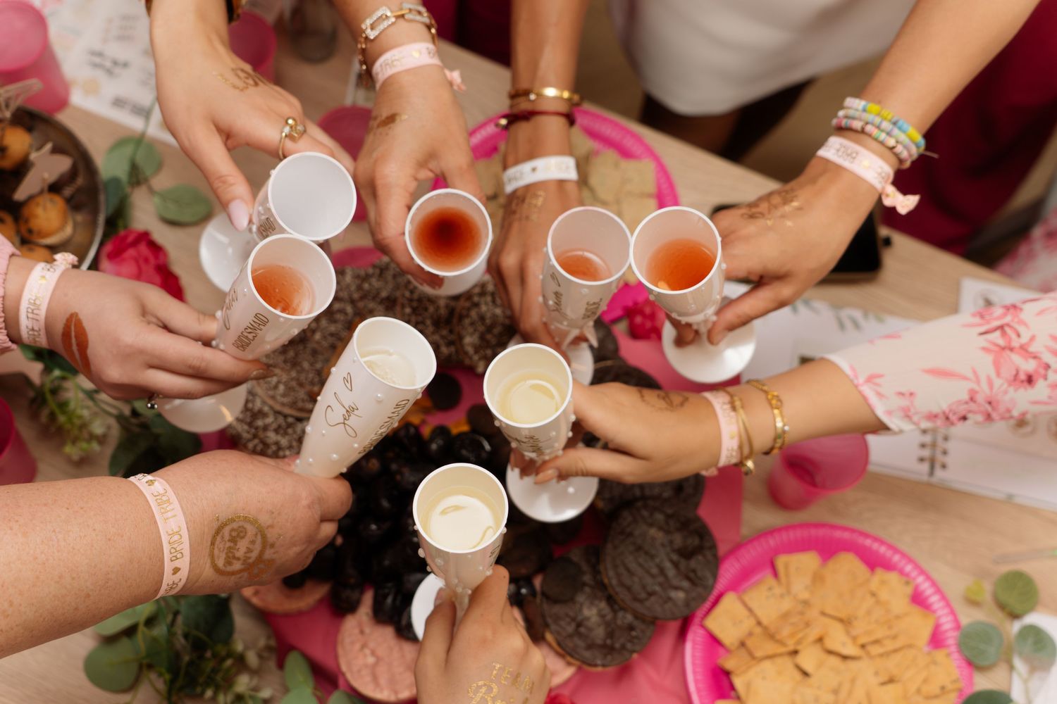 Group of women toasting with small cups at a decorated celebration table.