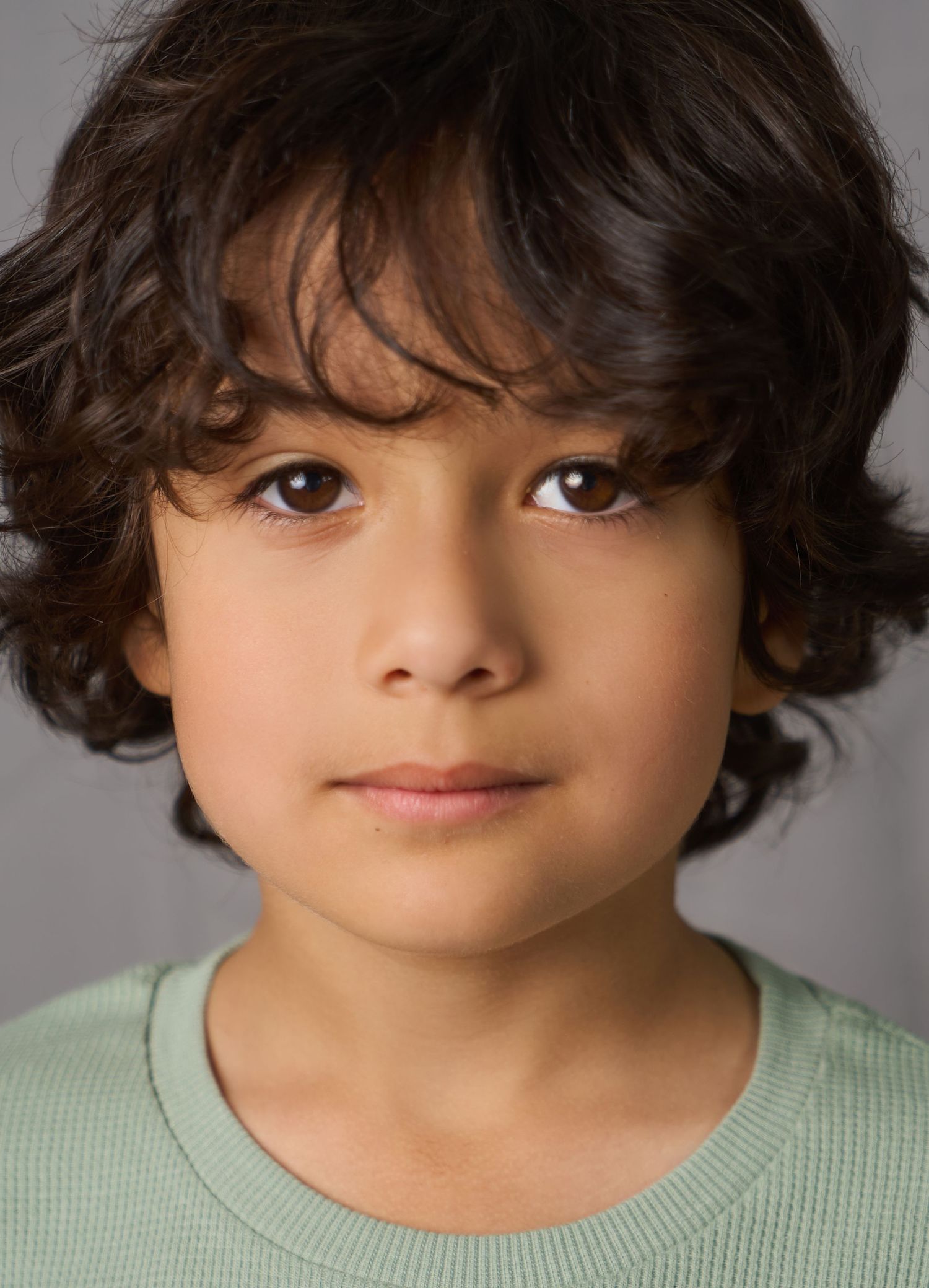 Boy with black hair, medium length headshot looking directly at the camera.