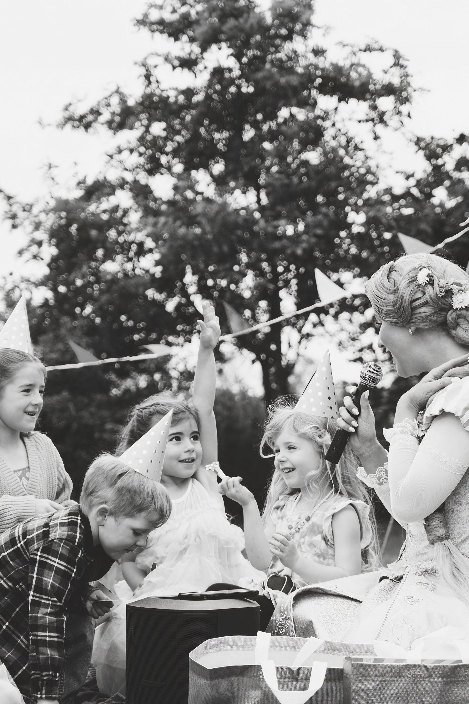 Black and white photo of children celebrating a birthday party outdoors with party hats.