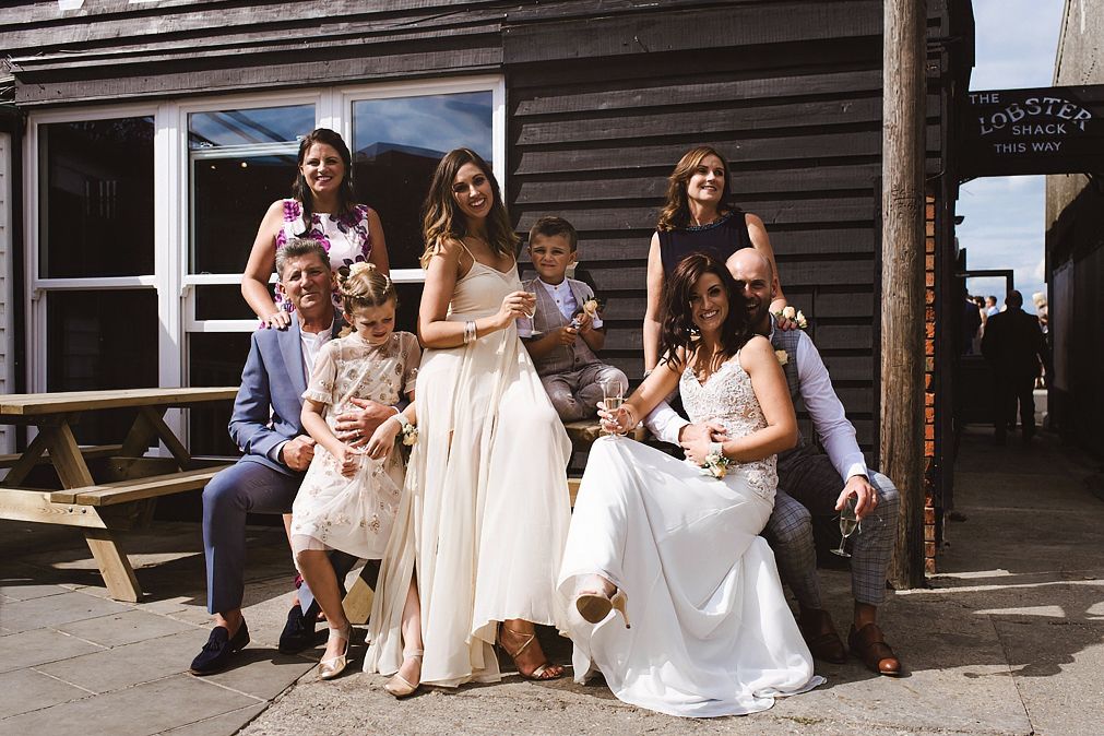 Wedding party group photo outside lobster shack with bride in flowing gown.