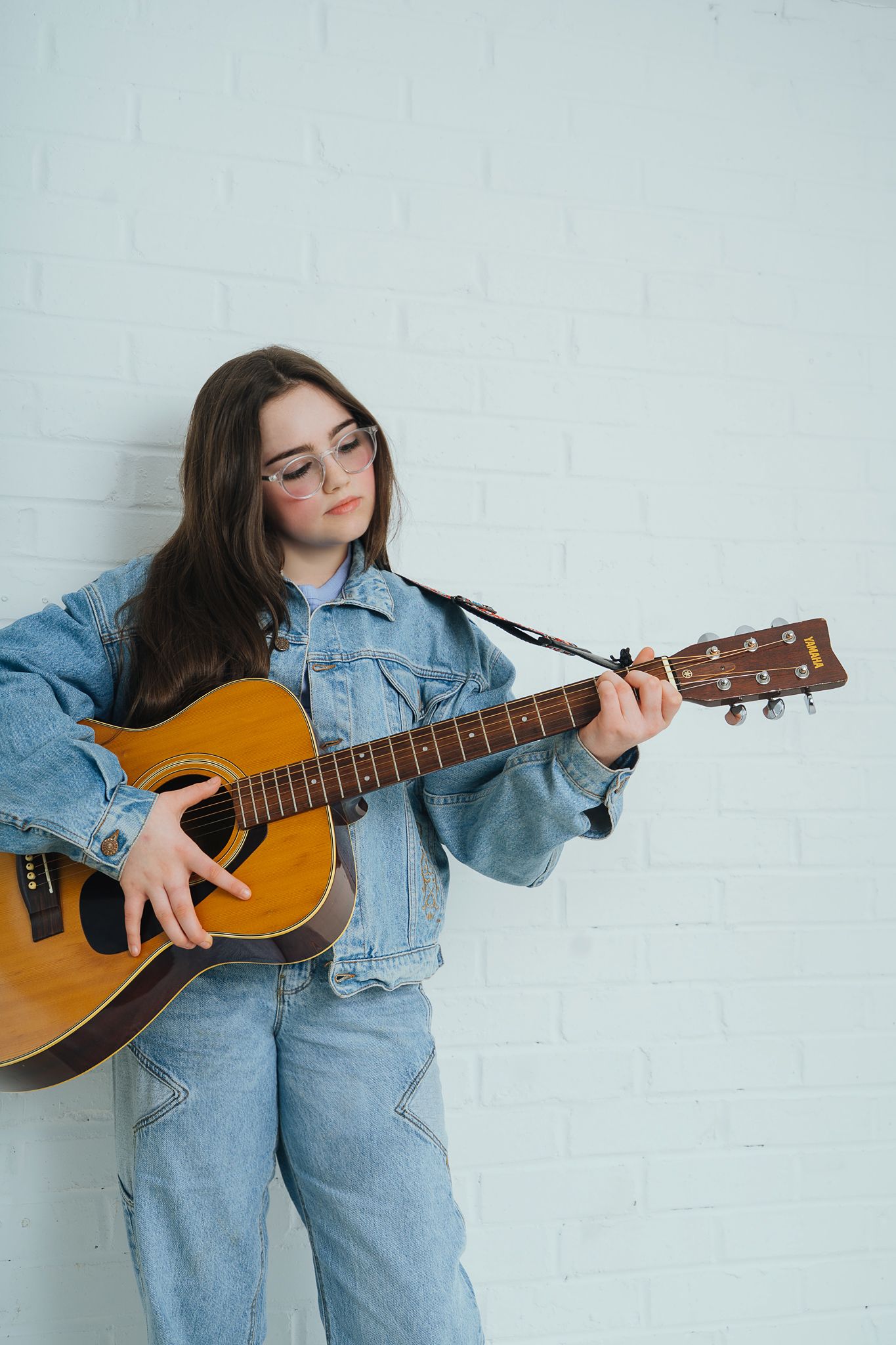 Young girl in denim holding a guitar in photo studio in Rochford, Essex.