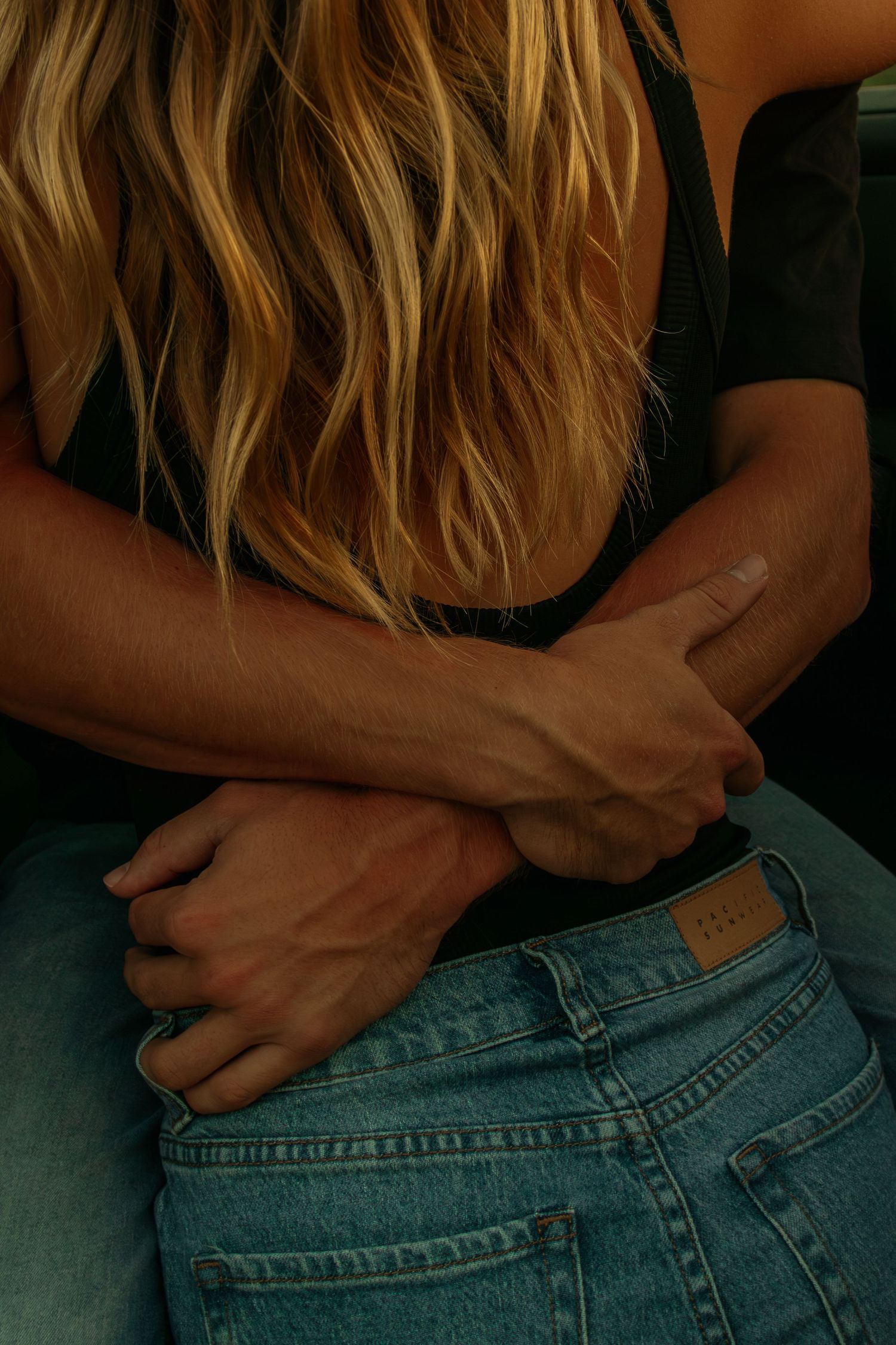 Close-up view of blonde wavy hair and denim jeans.