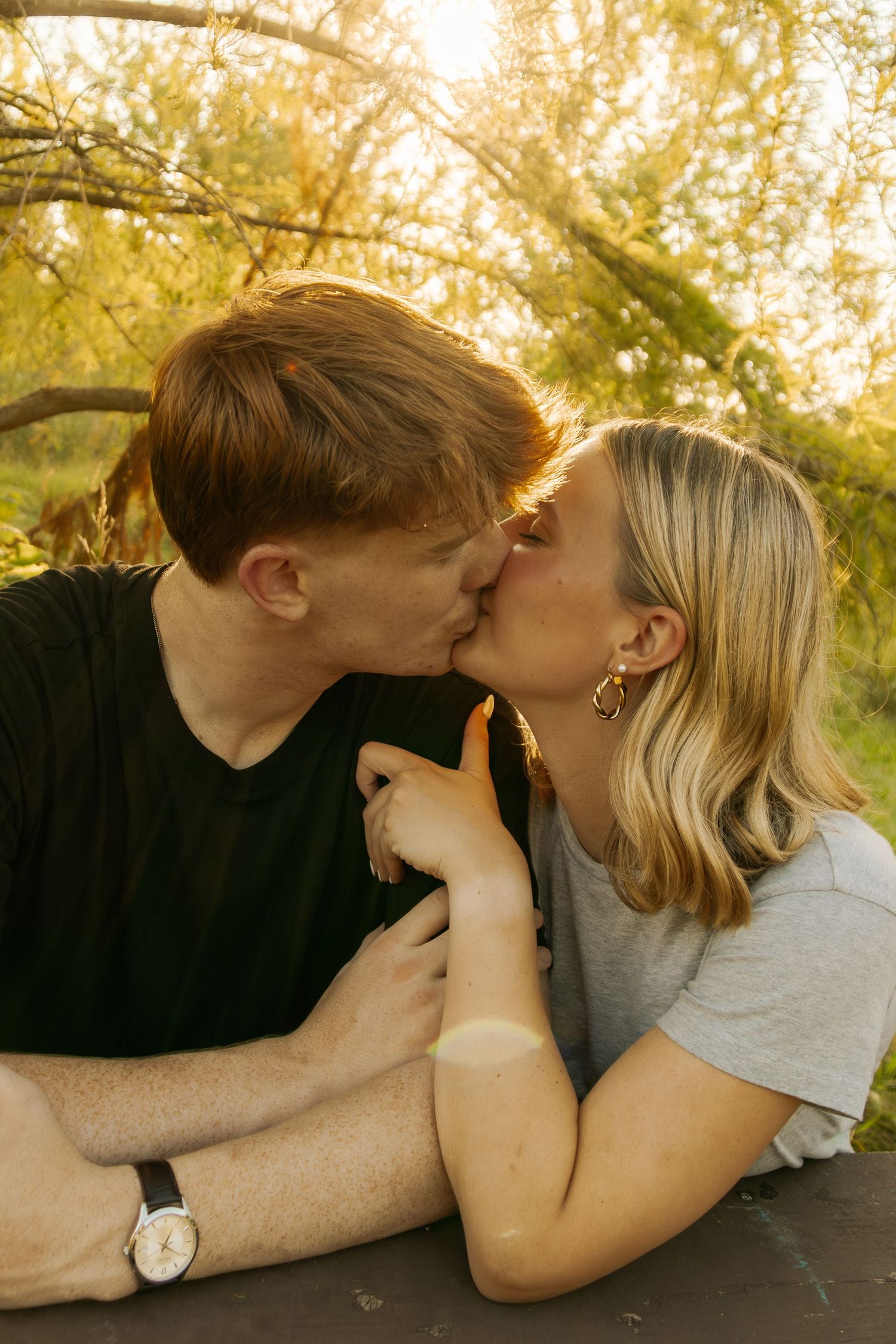 An intimate moment shared between two people lying in grass during golden hour.