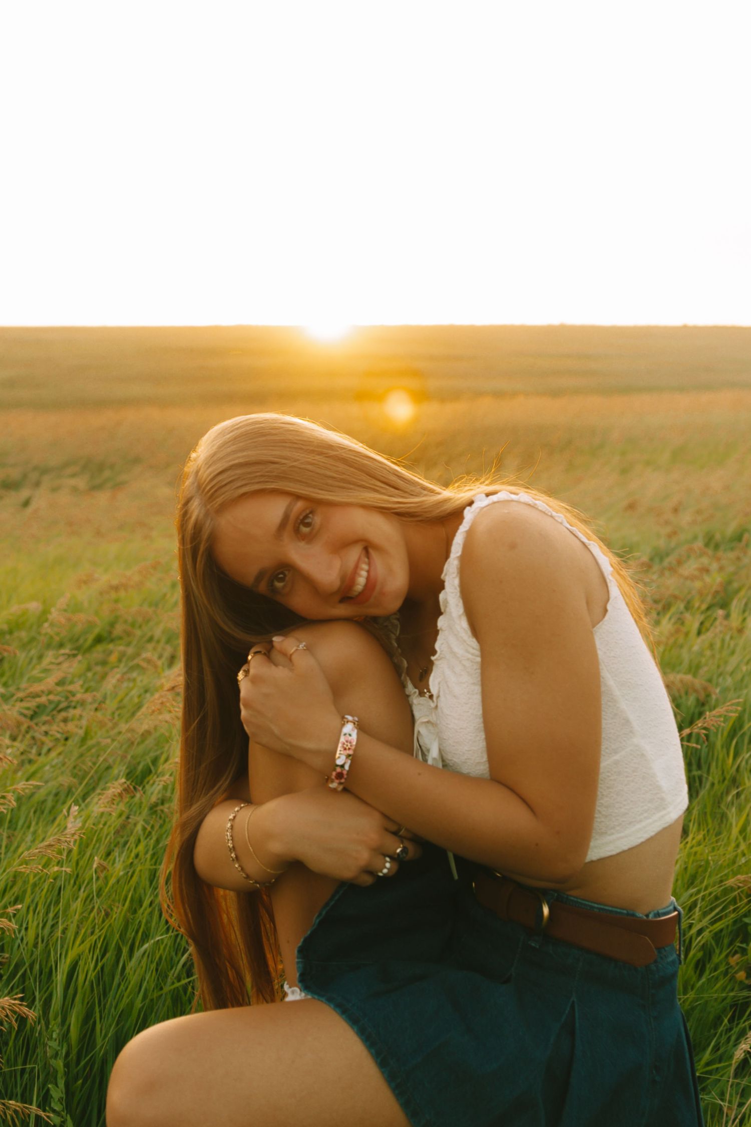 A dreamy golden hour photoshoot in a grassy field with soft sunlight creating a warm atmospheric glow.