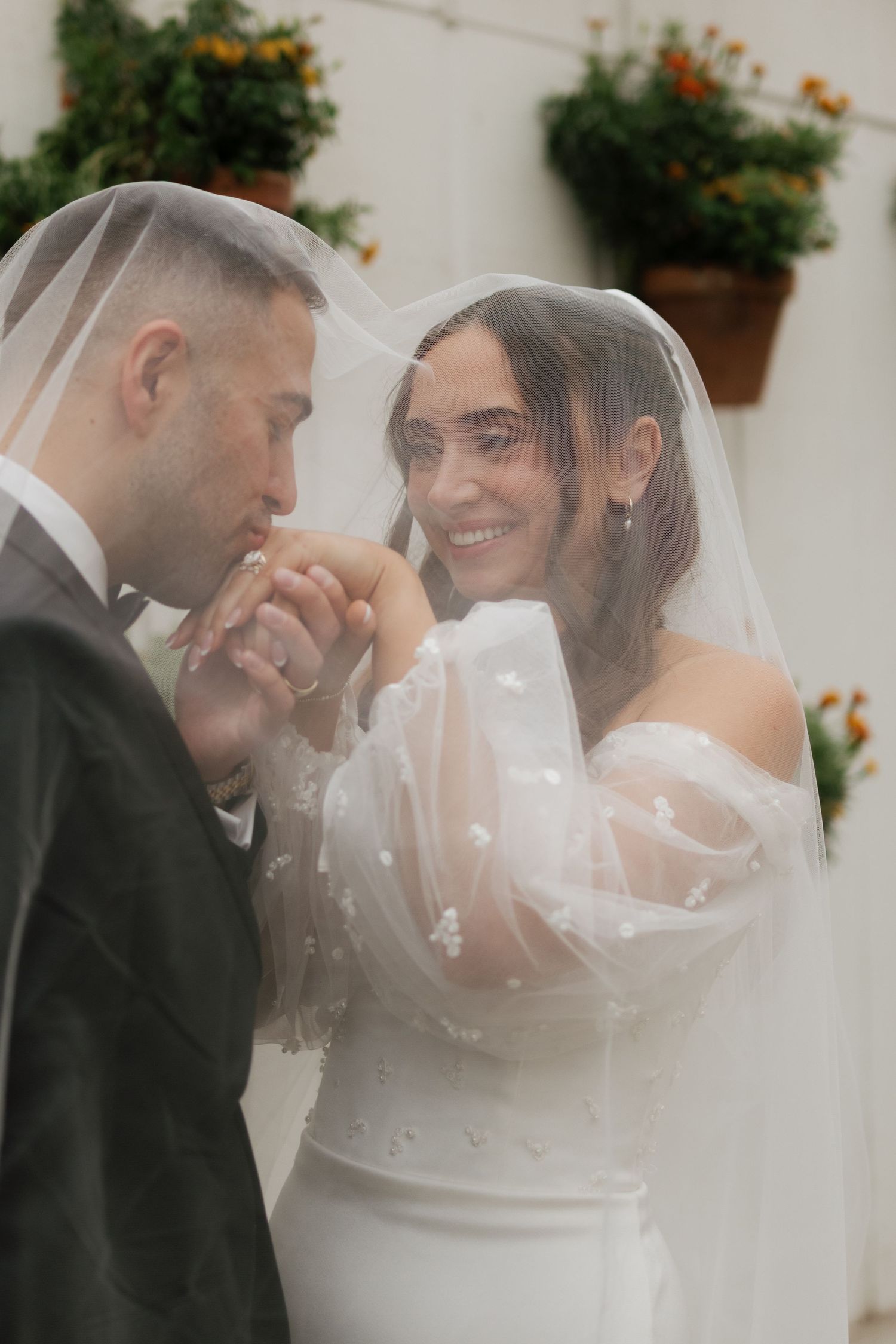 Romantic wedding portrait with delicate veil and orange flowers in background.