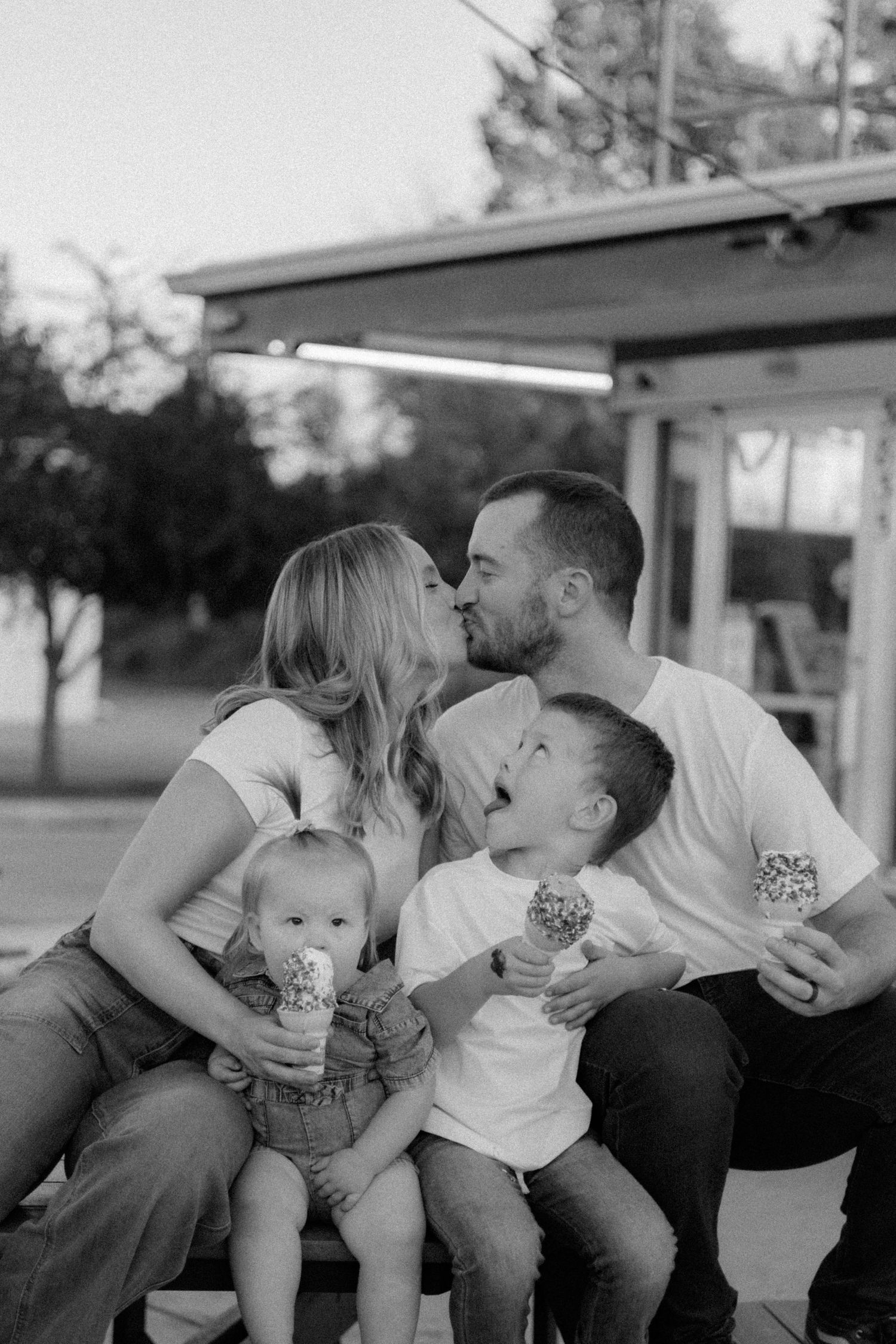 Family sharing affectionate moments together on an outdoor bench at sunset.