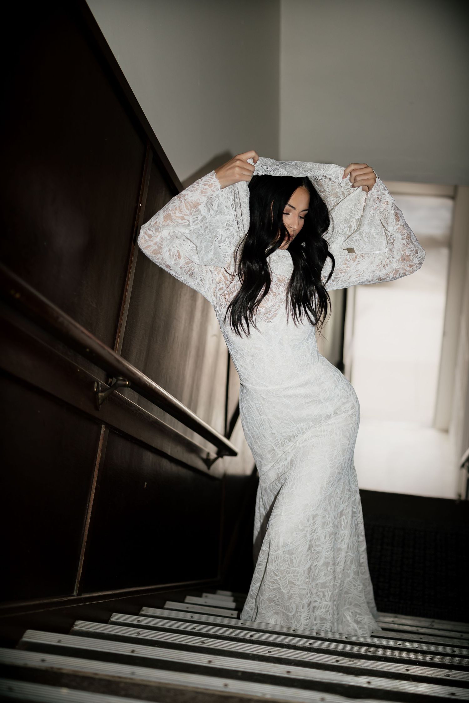 Artistic shots of a white lace wedding dress on stairs in dramatic lighting.