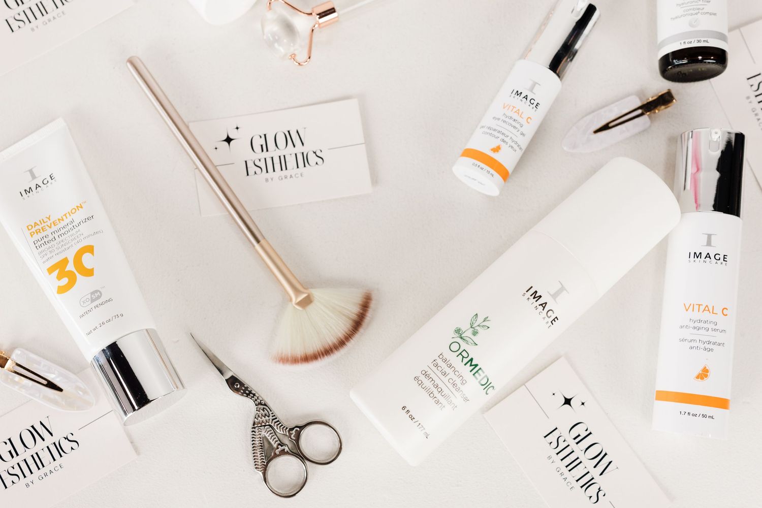 Flat lay of IMAGE skincare products and beauty accessories on white surface.