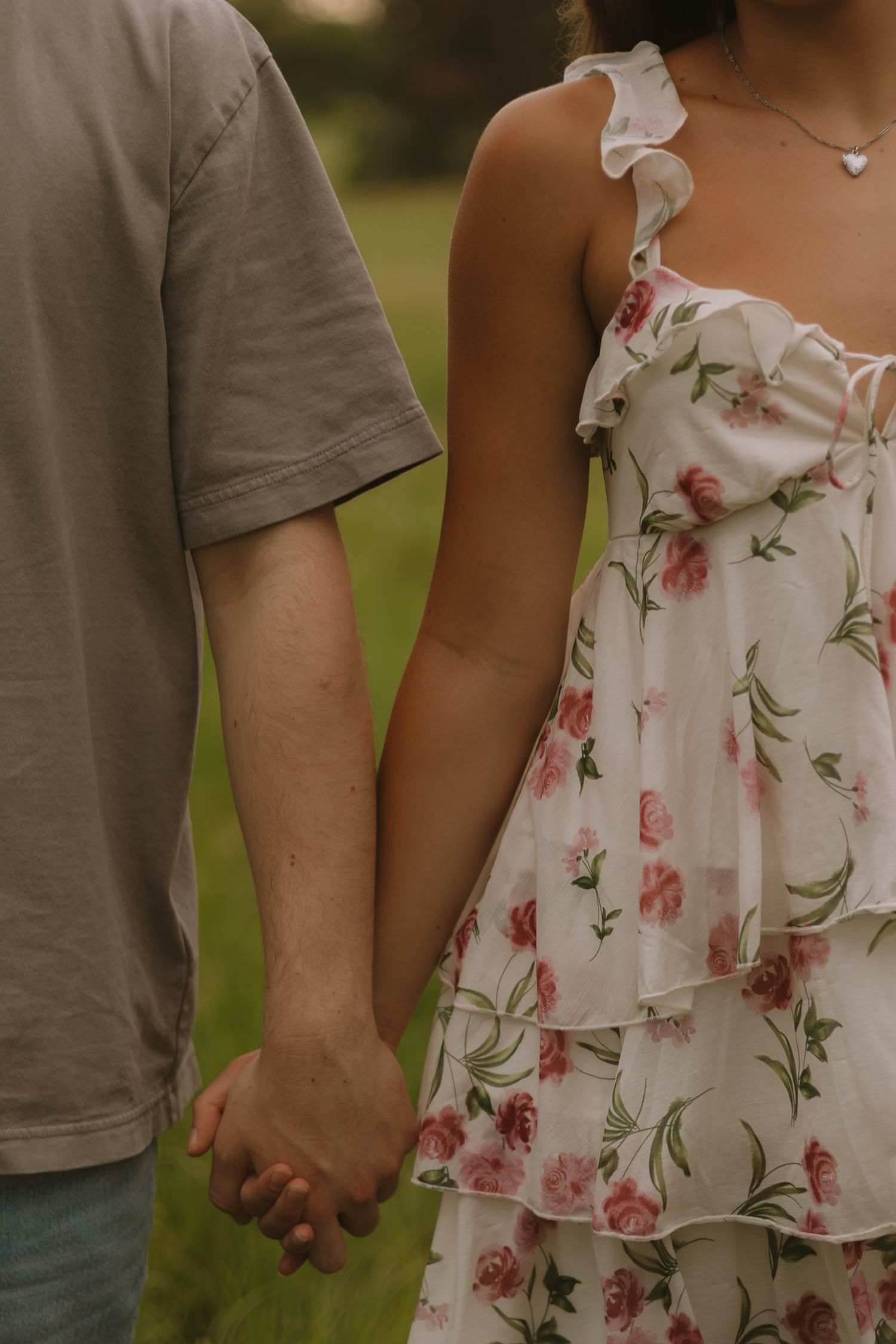 A couple holding hands wearing coordinated casual outfits with a floral summer dress detail.