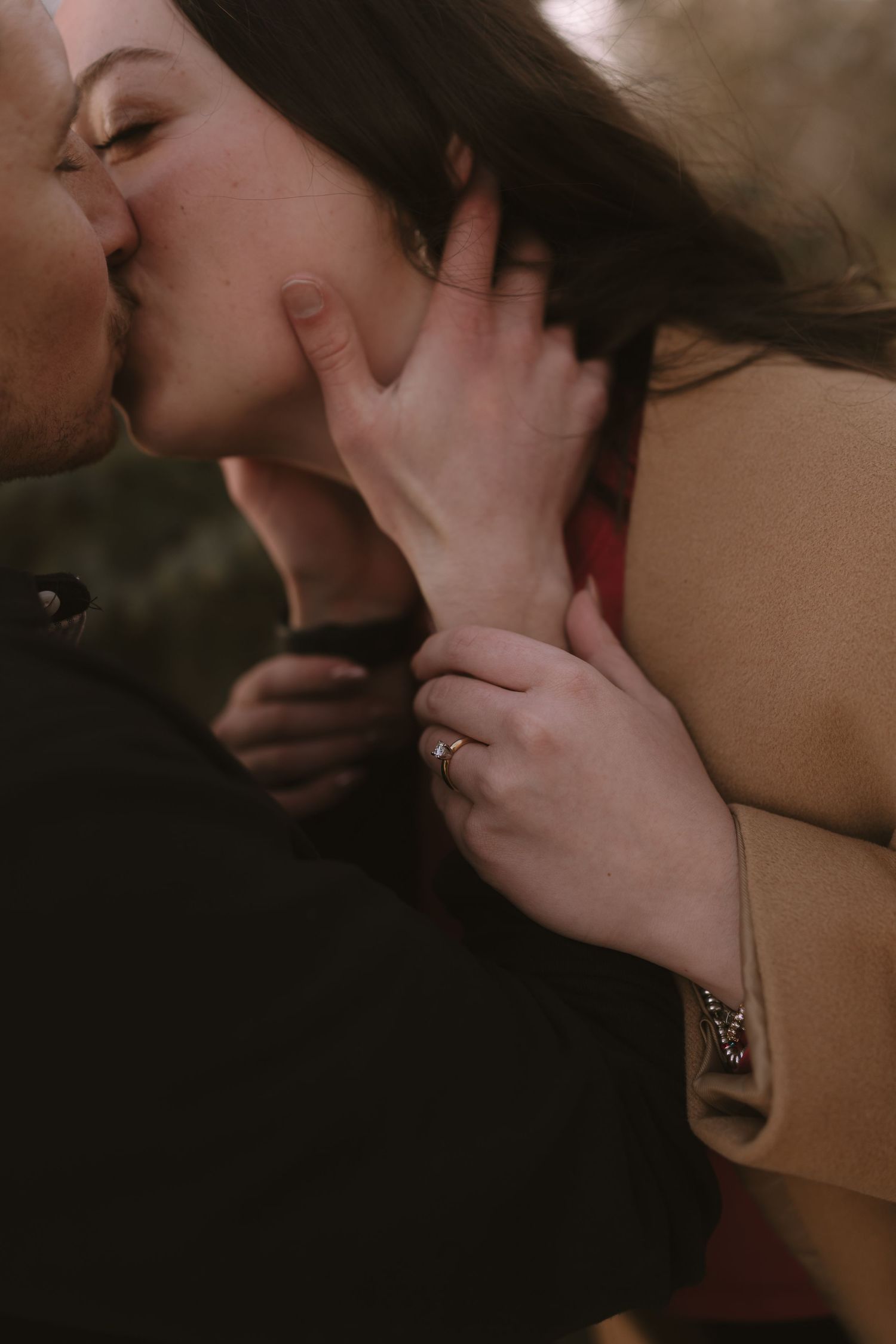 A close-up intimate moment captured showing hands and a gentle kiss.