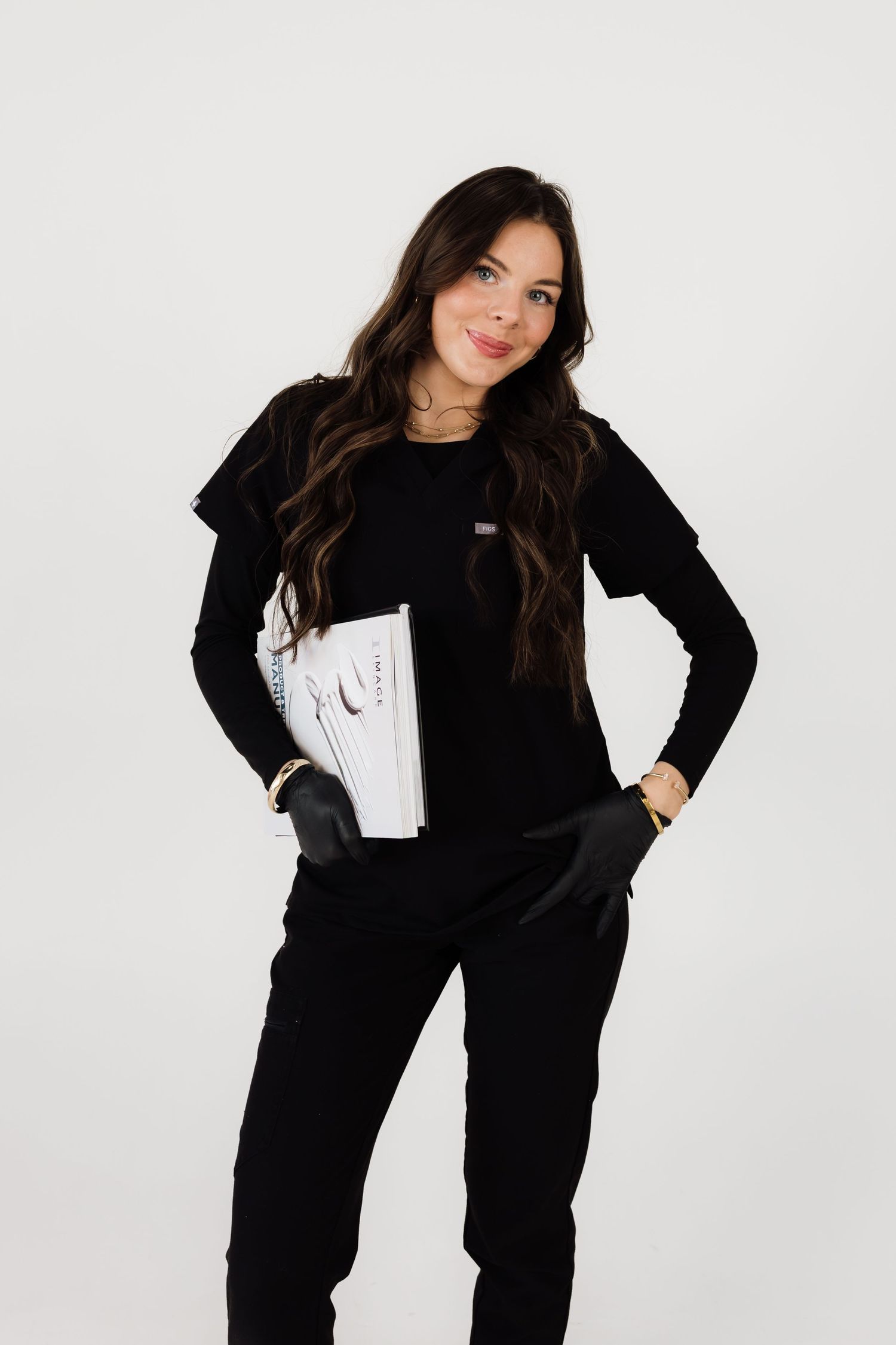 Fashion model in all-black outfit poses against white studio backdrop.