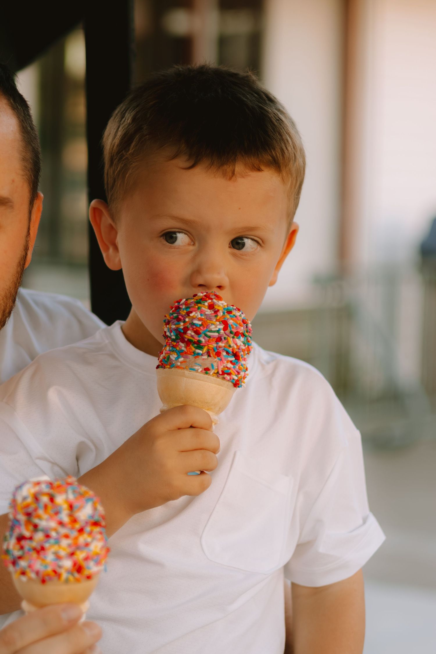 A child enjoying an ice cream cone covered in colorful sprinkles.