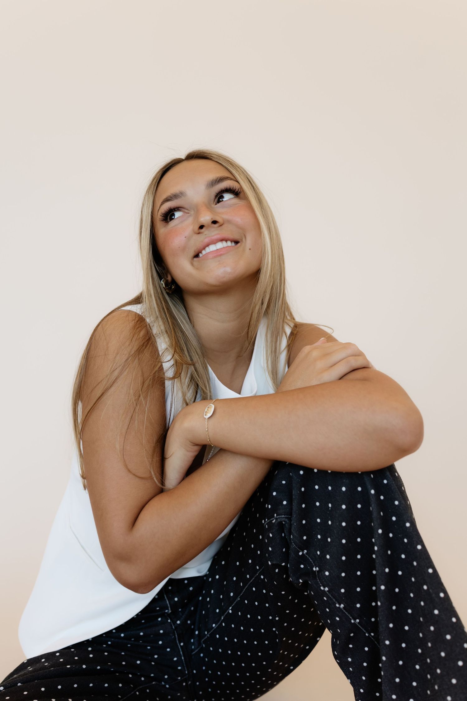 A series of expressive poses in a black polka dot dress against a light background.