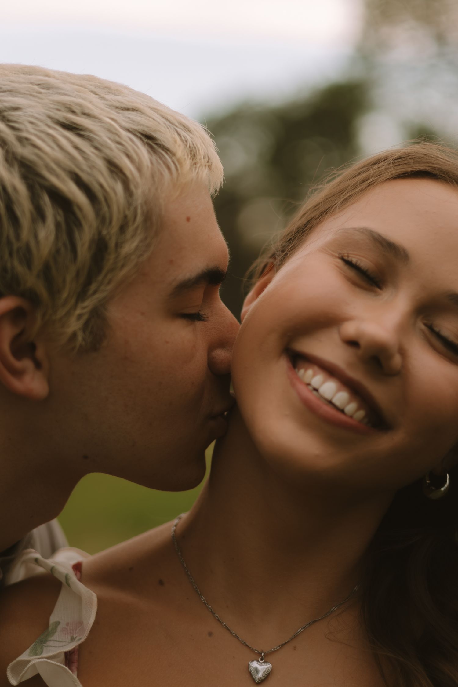 An intimate close-up portrait capturing a tender moment between a couple outdoors.