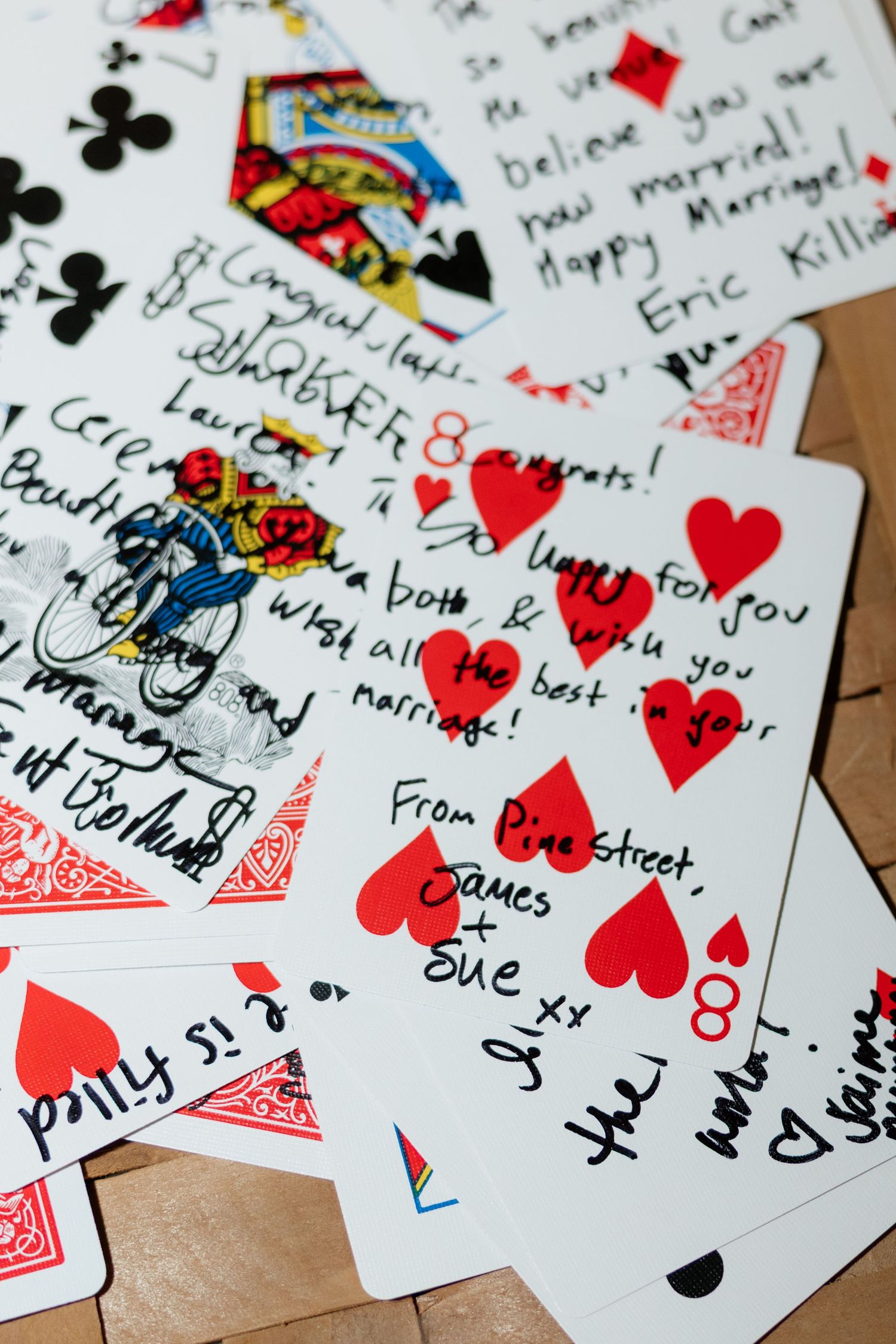 Playing cards decorated with handwritten wedding messages and red hearts.