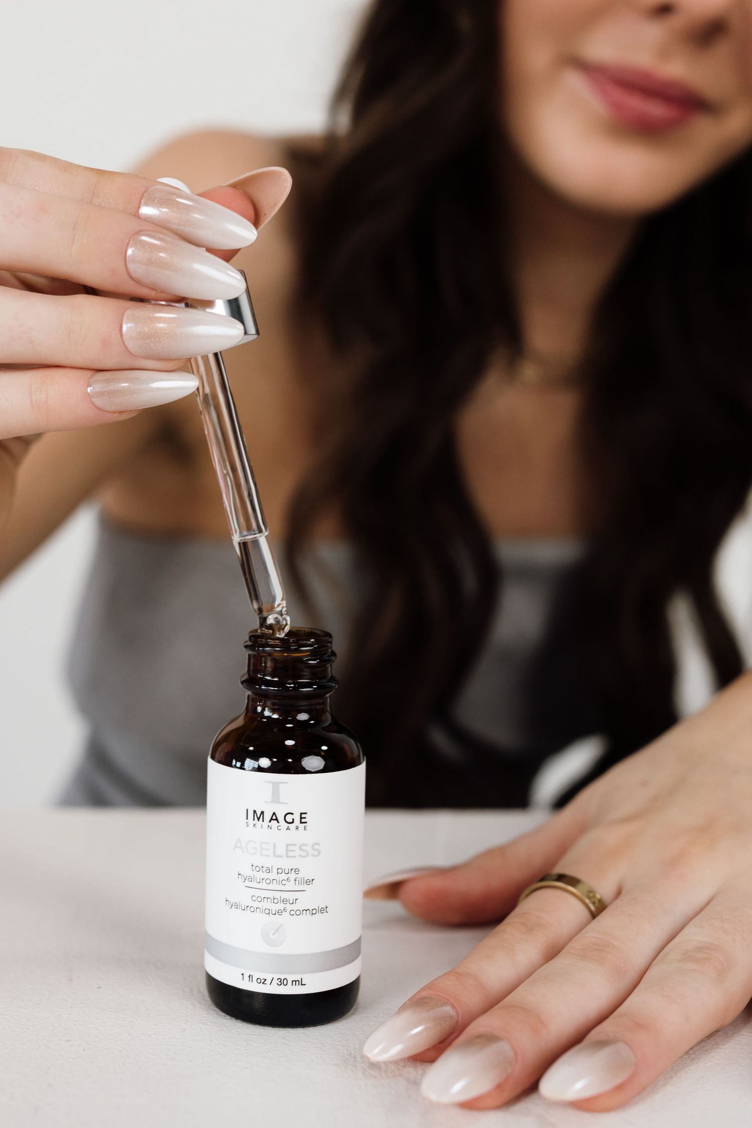Hands demonstrating use of IMAGE skincare product dropper bottle.