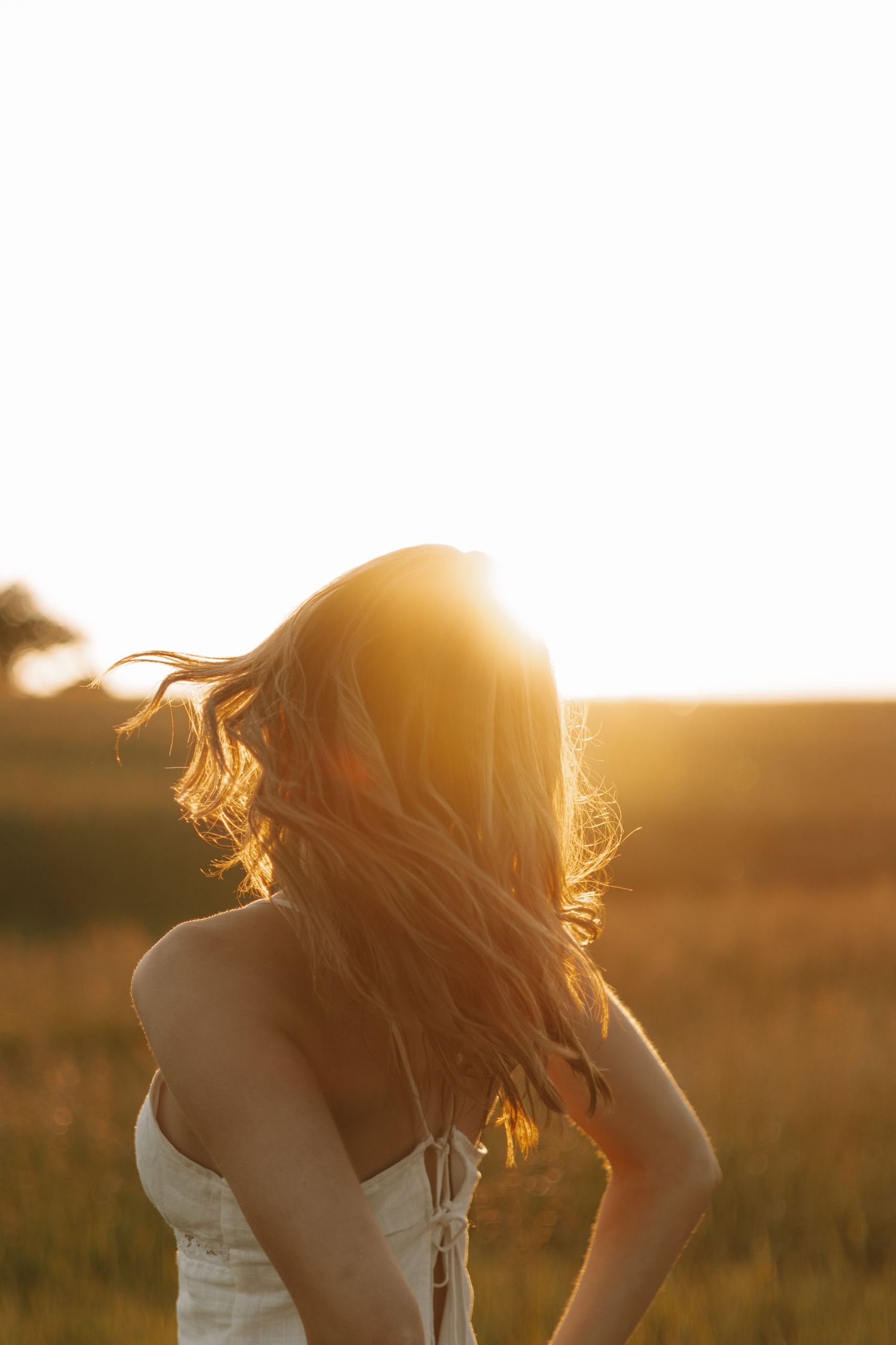 Ethereal sunlit portrait session in golden field at sunset.