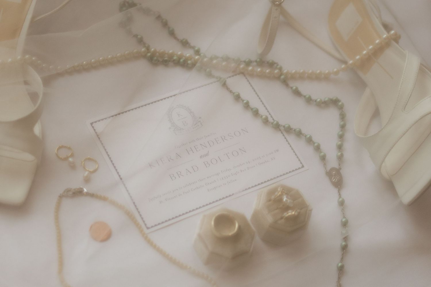 Wedding invitation with delicate pearl necklace and accessories on white background.