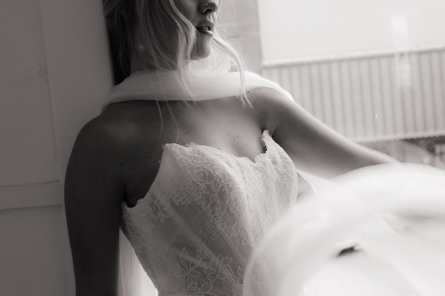 A romantic black and white portrait of a couple in wedding attire embracing tenderly.
