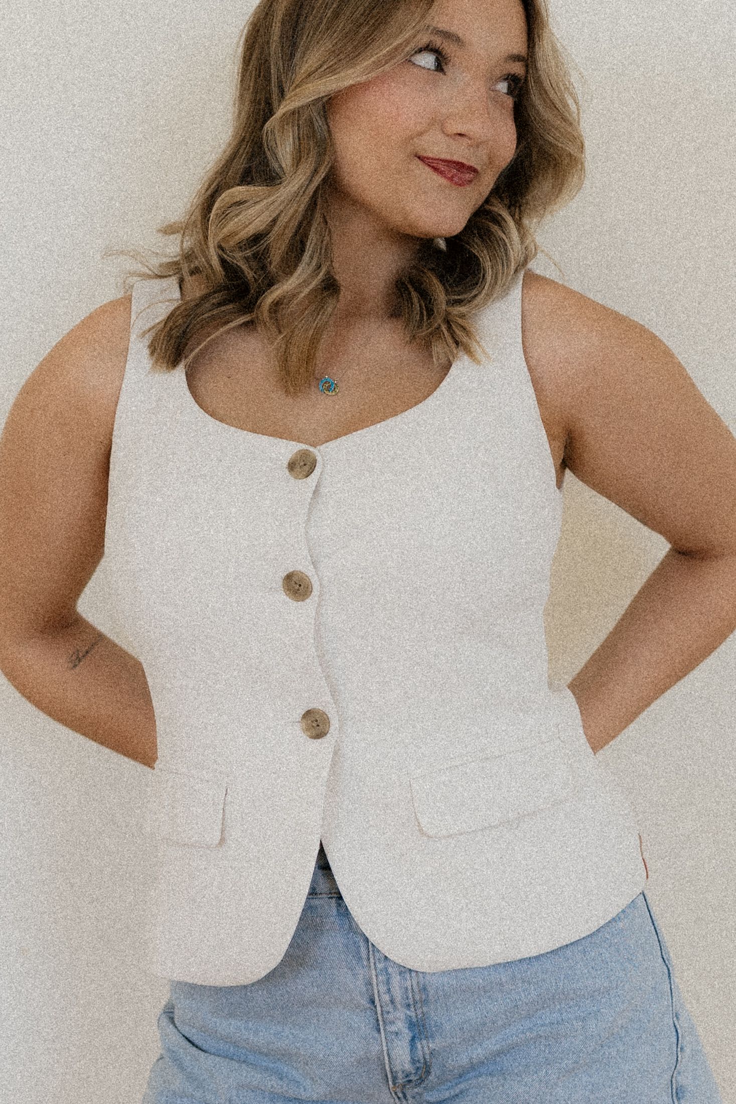 A white cropped button-up sleeveless top styled with light wash denim jeans shown from different angles.