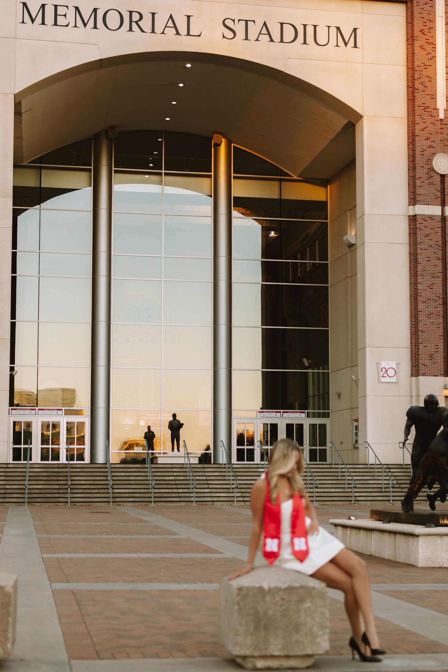 Memorial Stadium entrance with graduate posing on concrete steps.