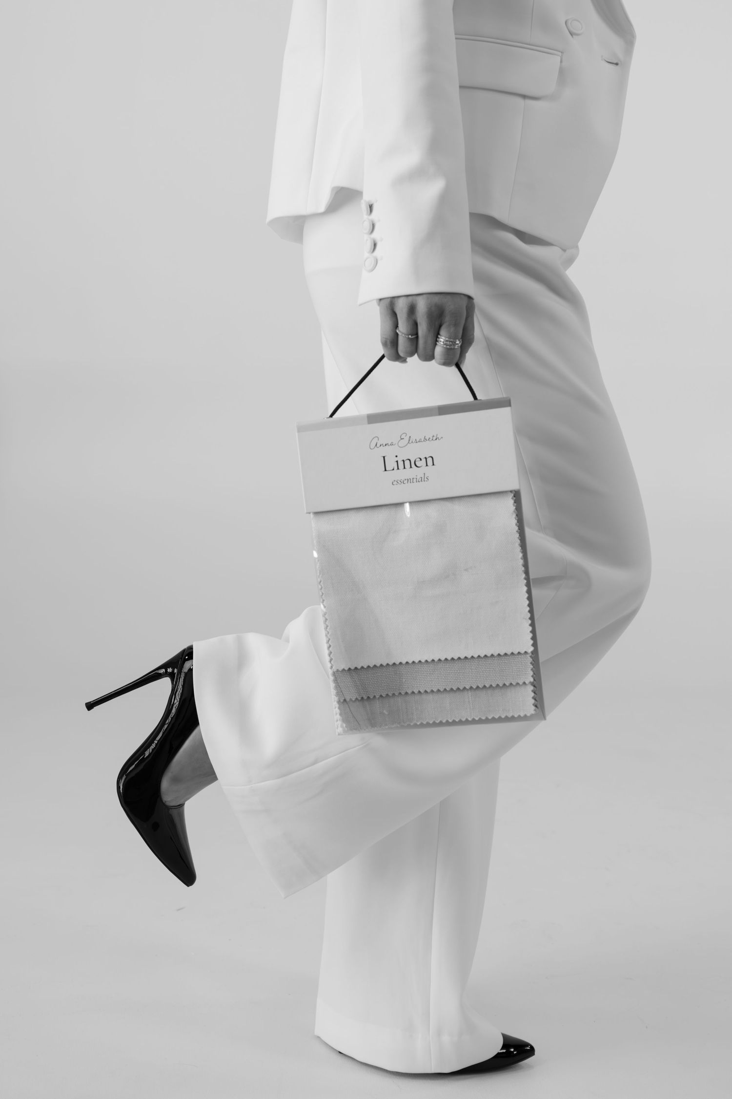 Fashion detail shots of white clothing and black heels against light background.