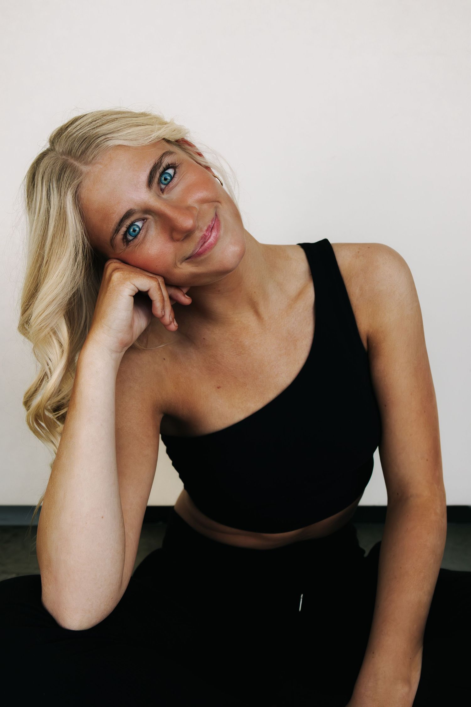Expressive studio portraits with black athletic wear against minimalist white backdrop.