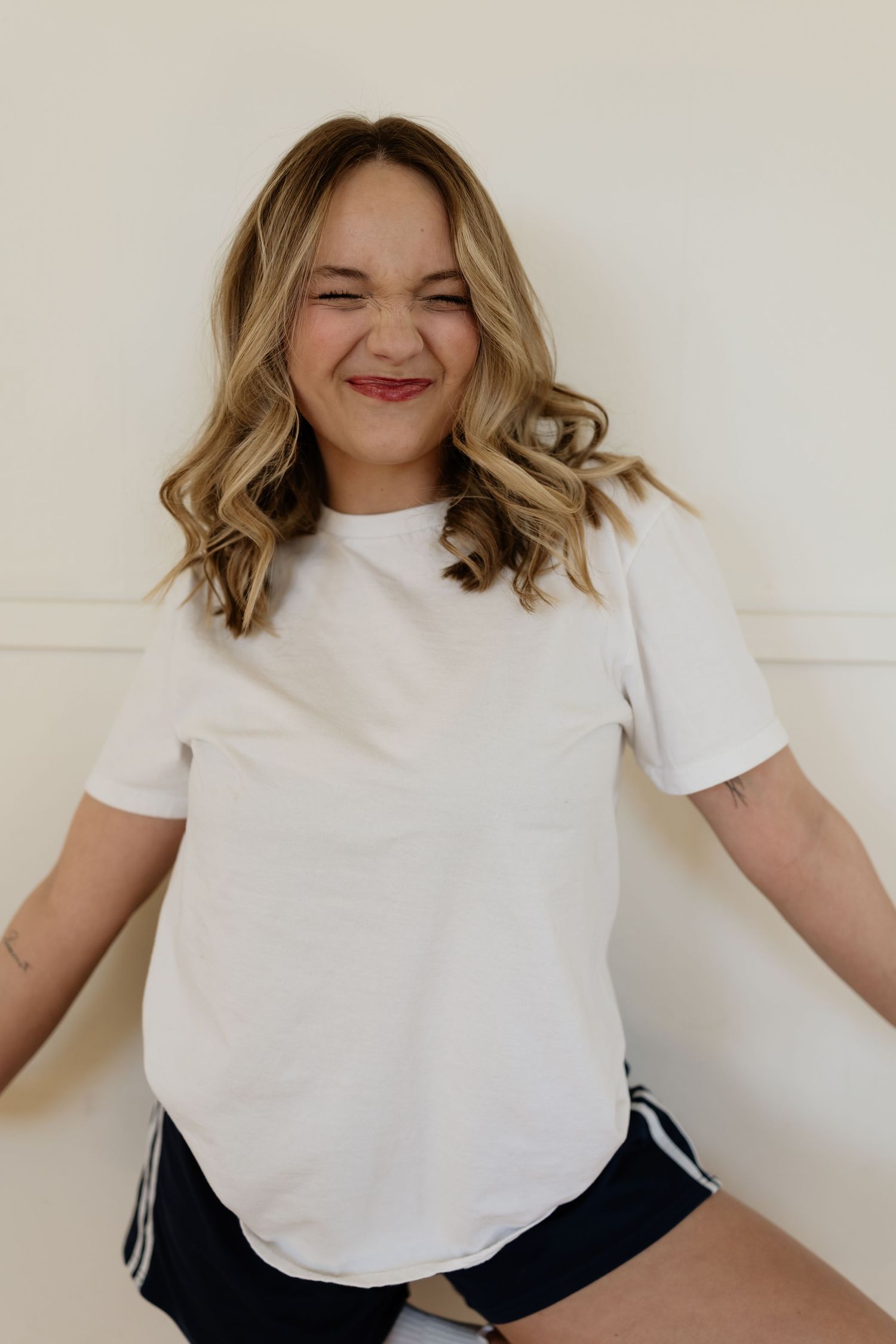 Four sequential photos show someone in a white t-shirt and dark pants expressing joyful movement against a light wall.