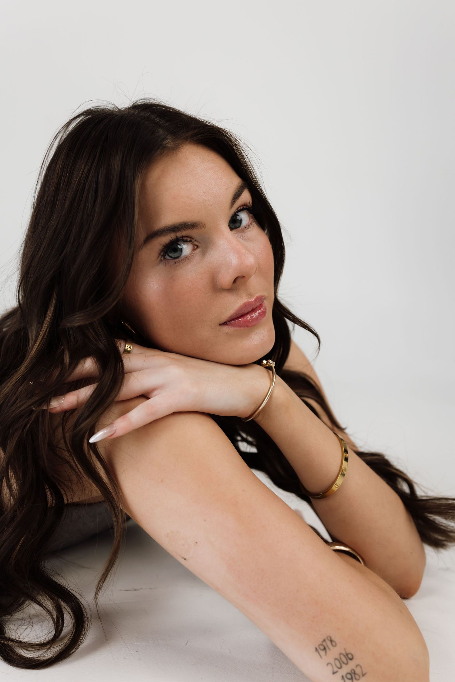 Fashion model poses in white studio wearing delicate jewelry.