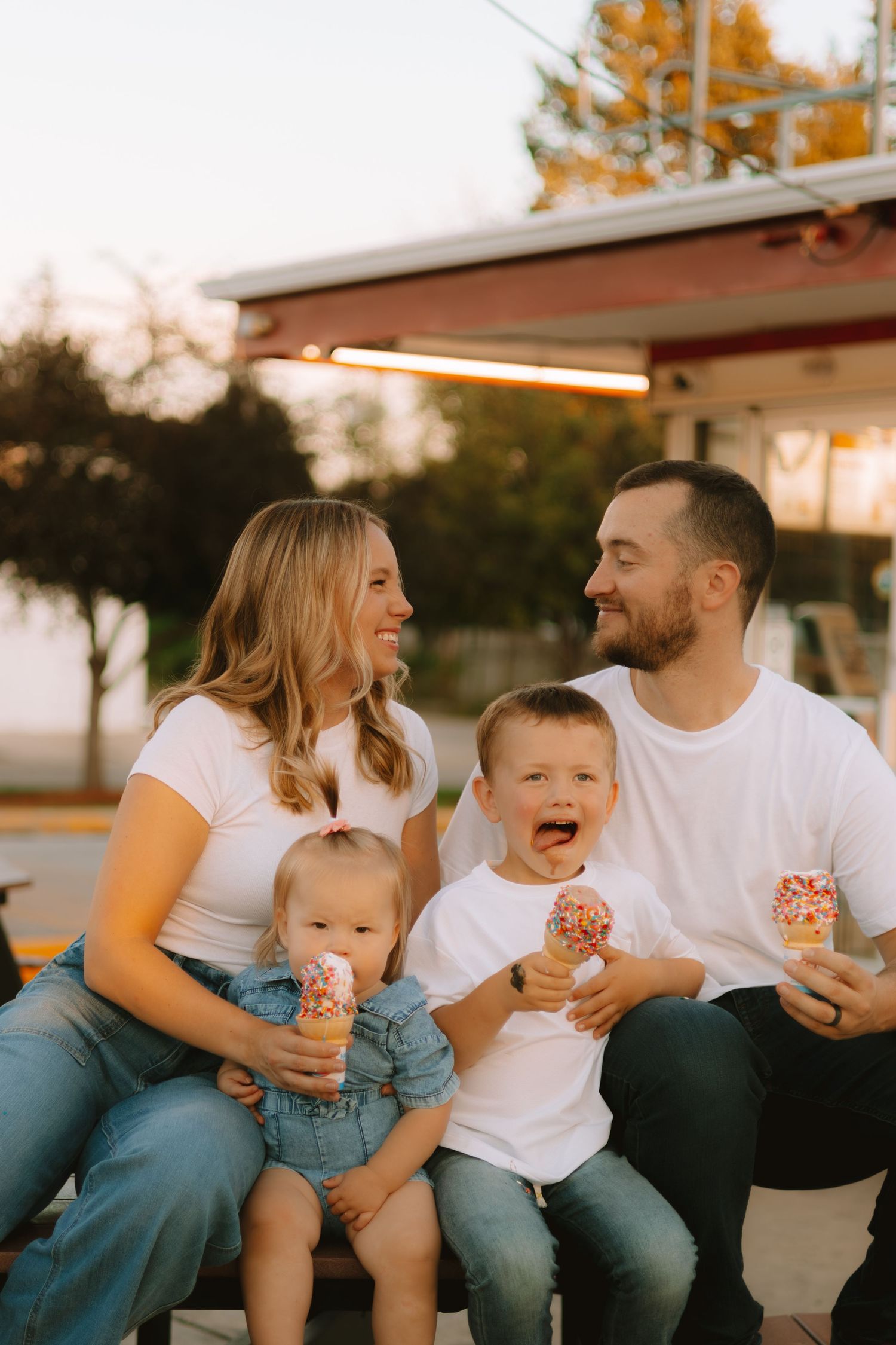 A family shares ice cream cones together outside at sunset.