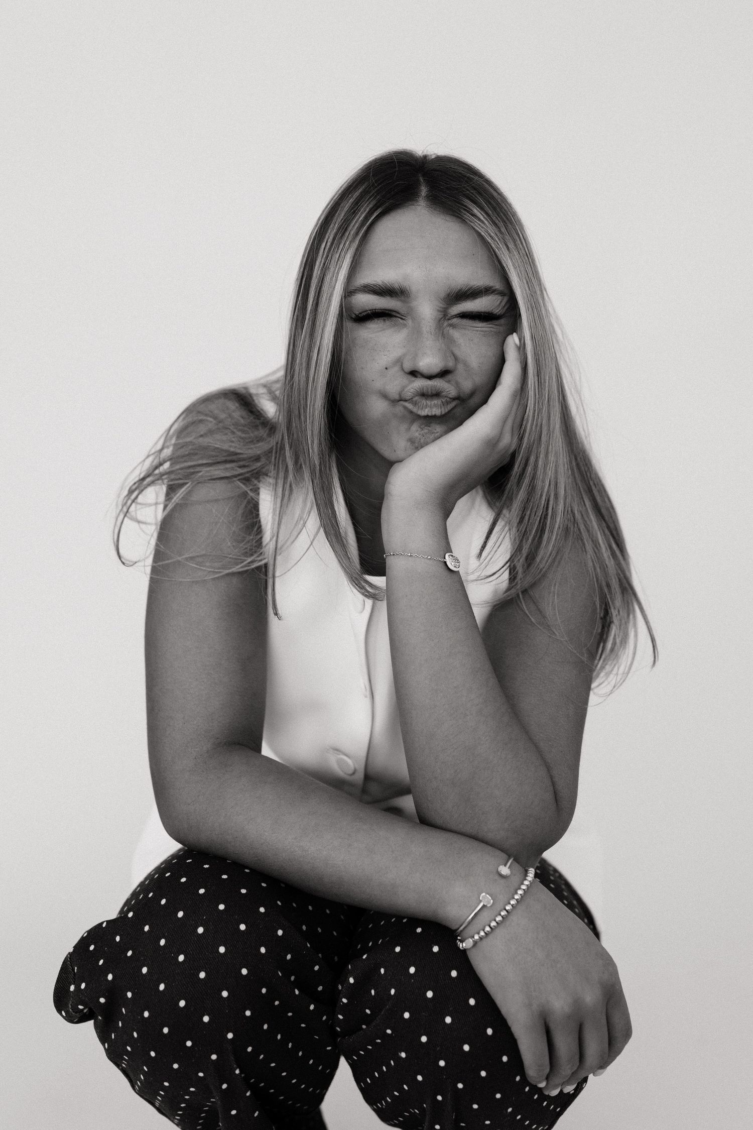 A black and white photo series showing a person in a polka dot outfit expressing different playful emotions.