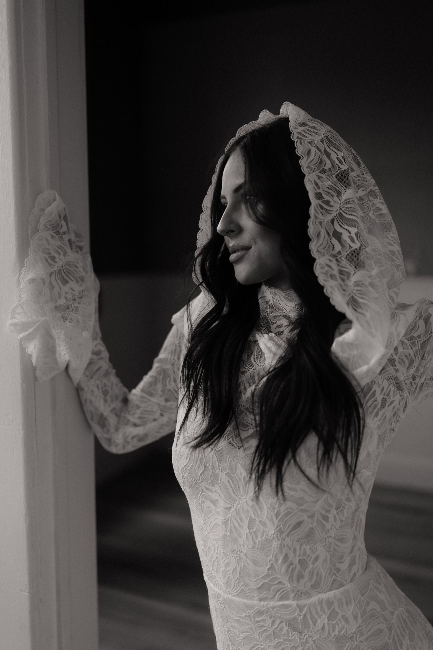 Dramatic black and white photos of a lace wedding dress with flowing sleeves.