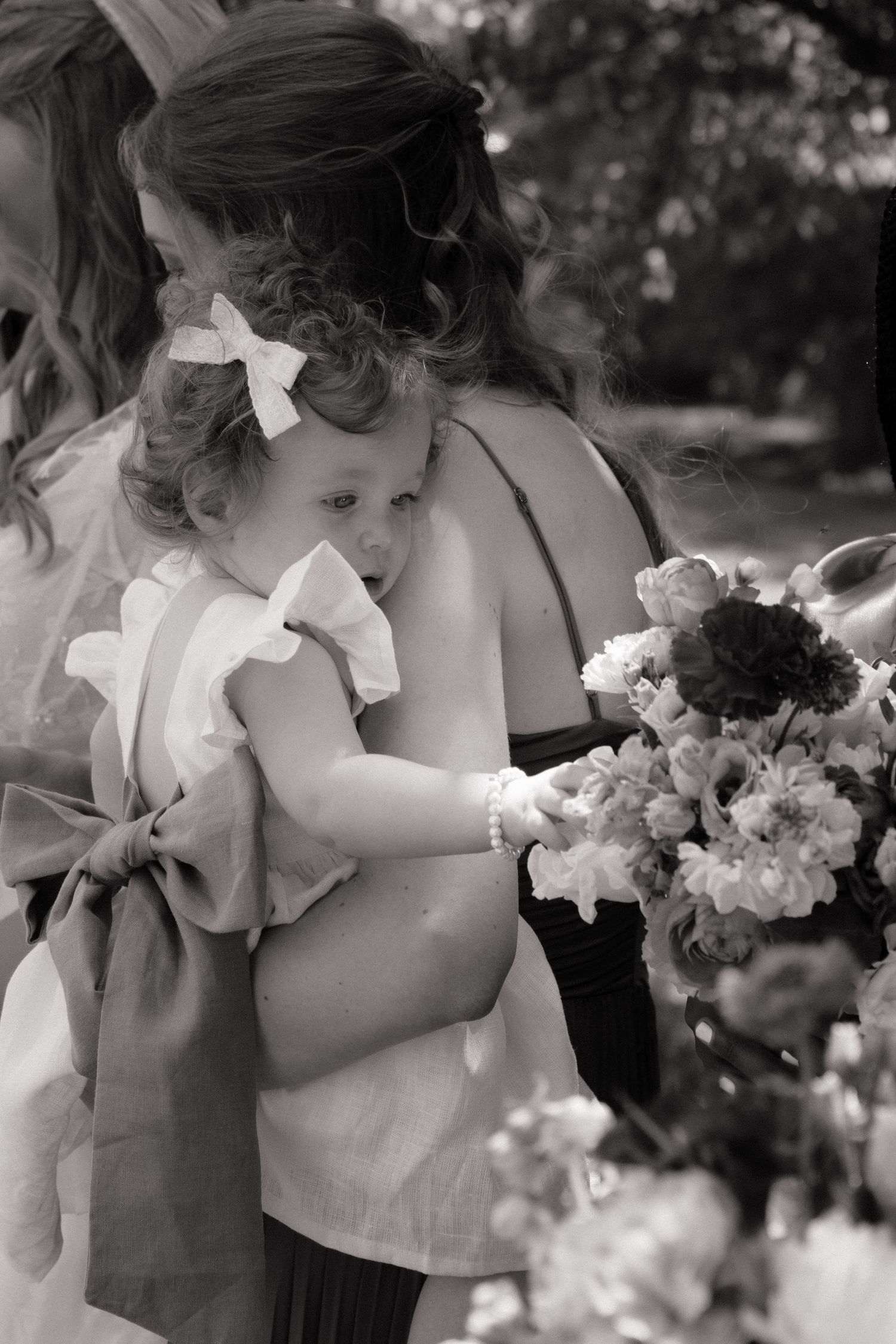 A series of black and white photos showing someone smelling a bouquet of flowers in a garden setting.