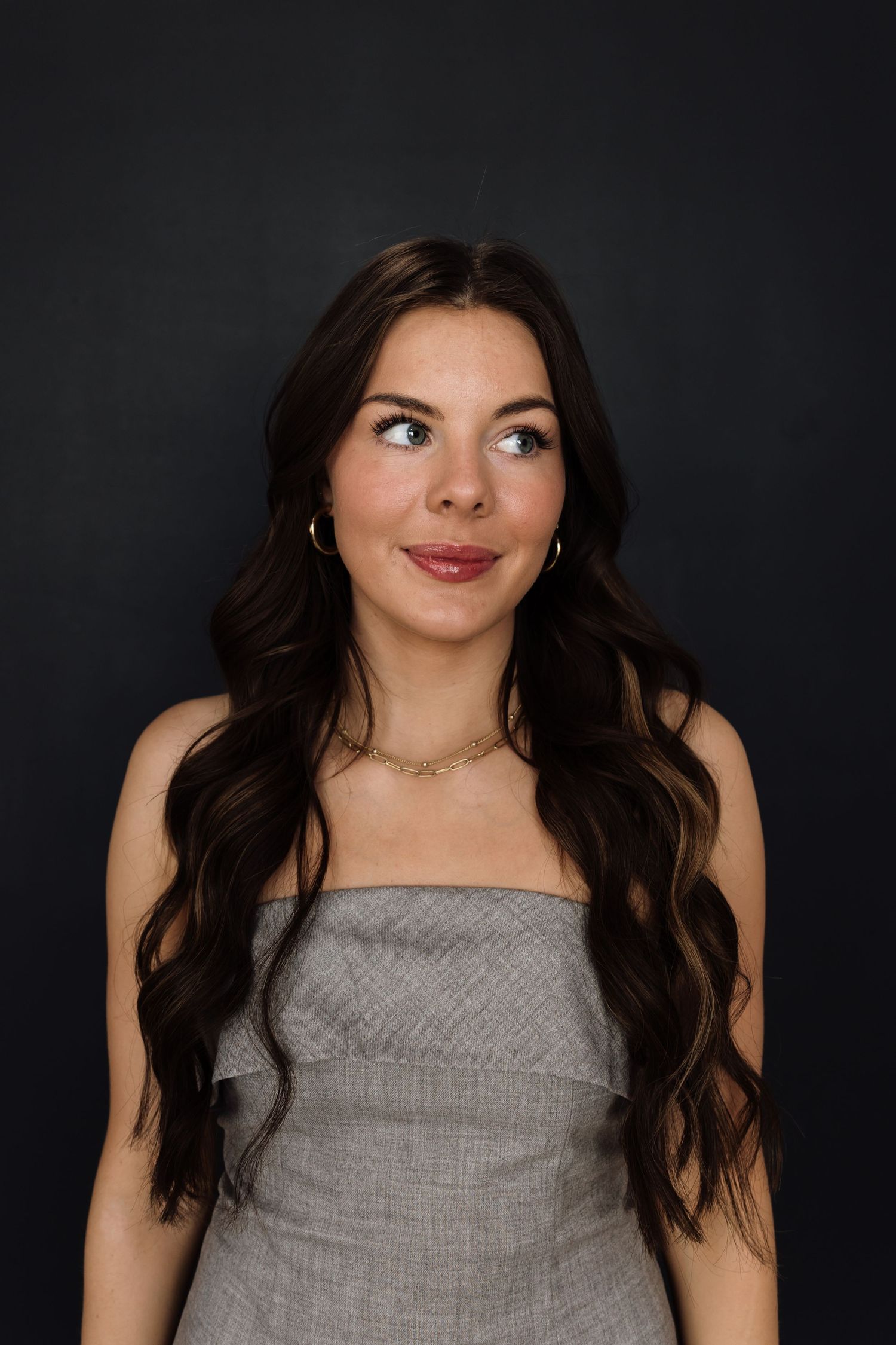 Dramatic portrait series against dark background wearing grey top.