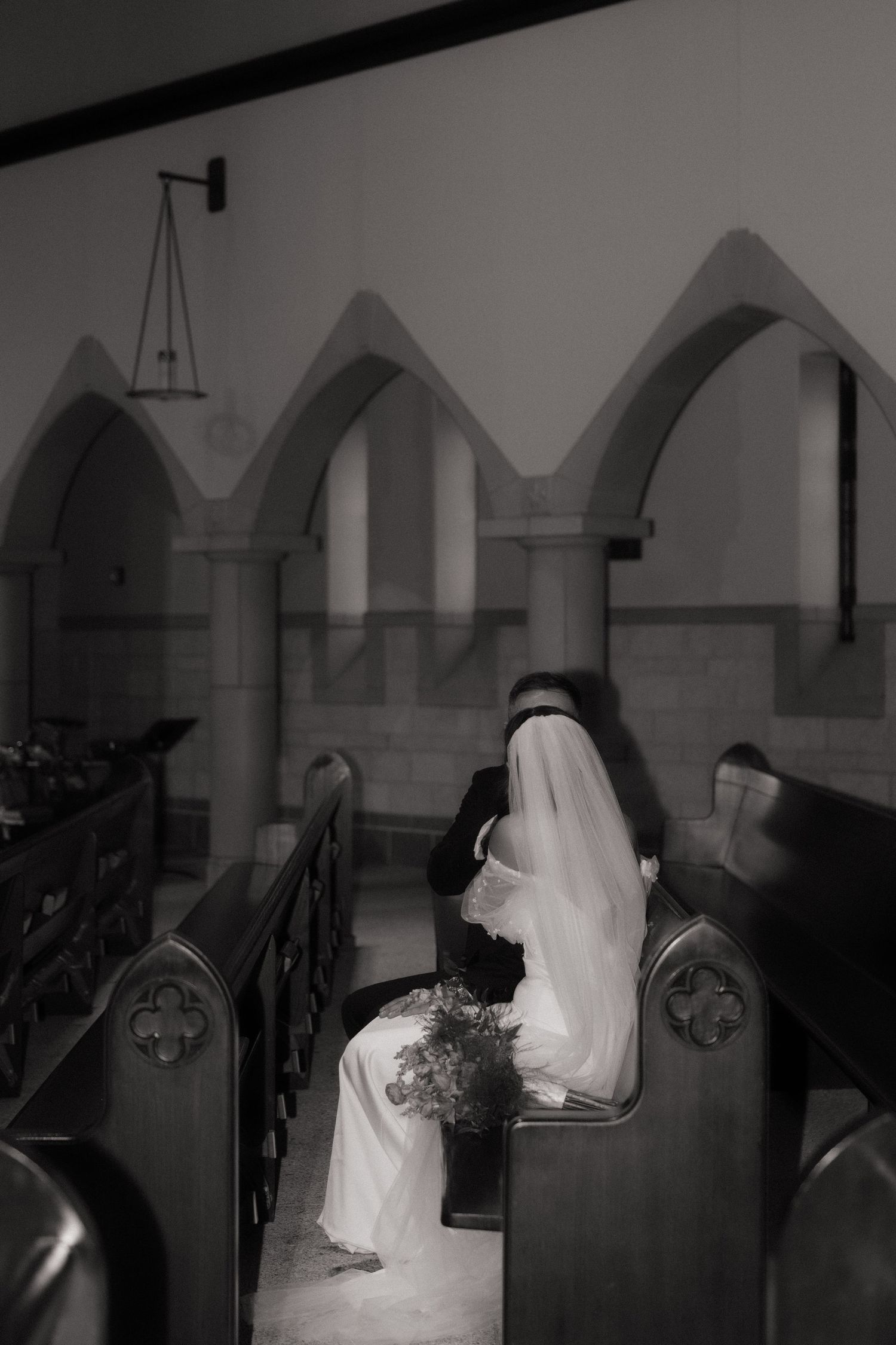 Dramatic black and white wedding photo in church with gothic arches.