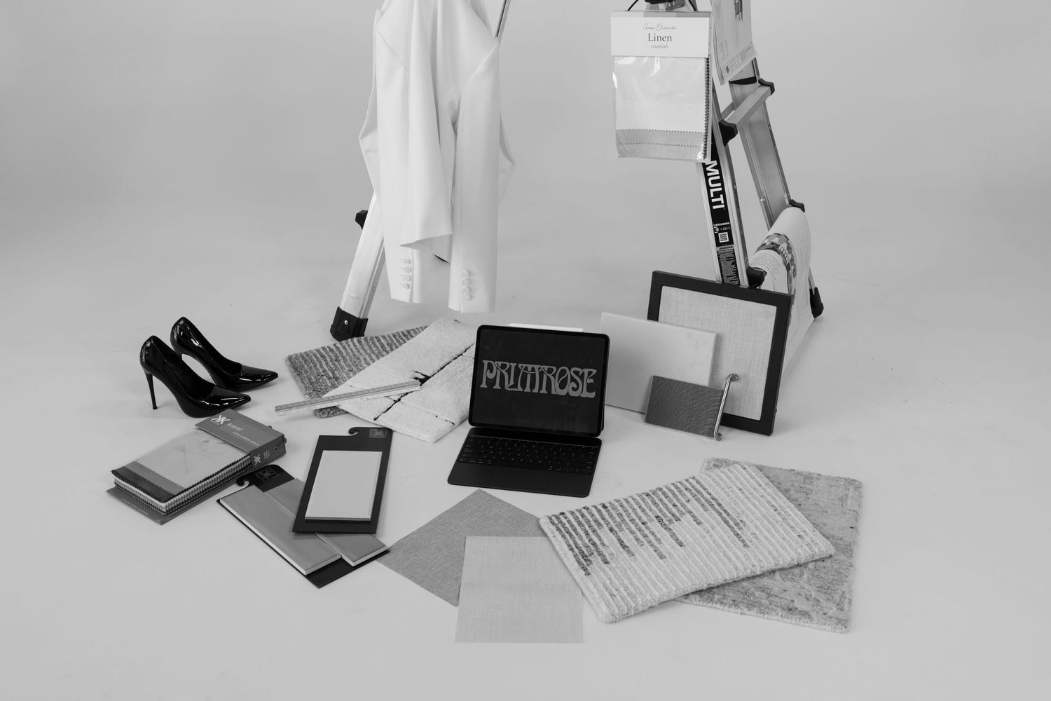 Flat lay of business items including books, papers and shoes arranged on light surface.
