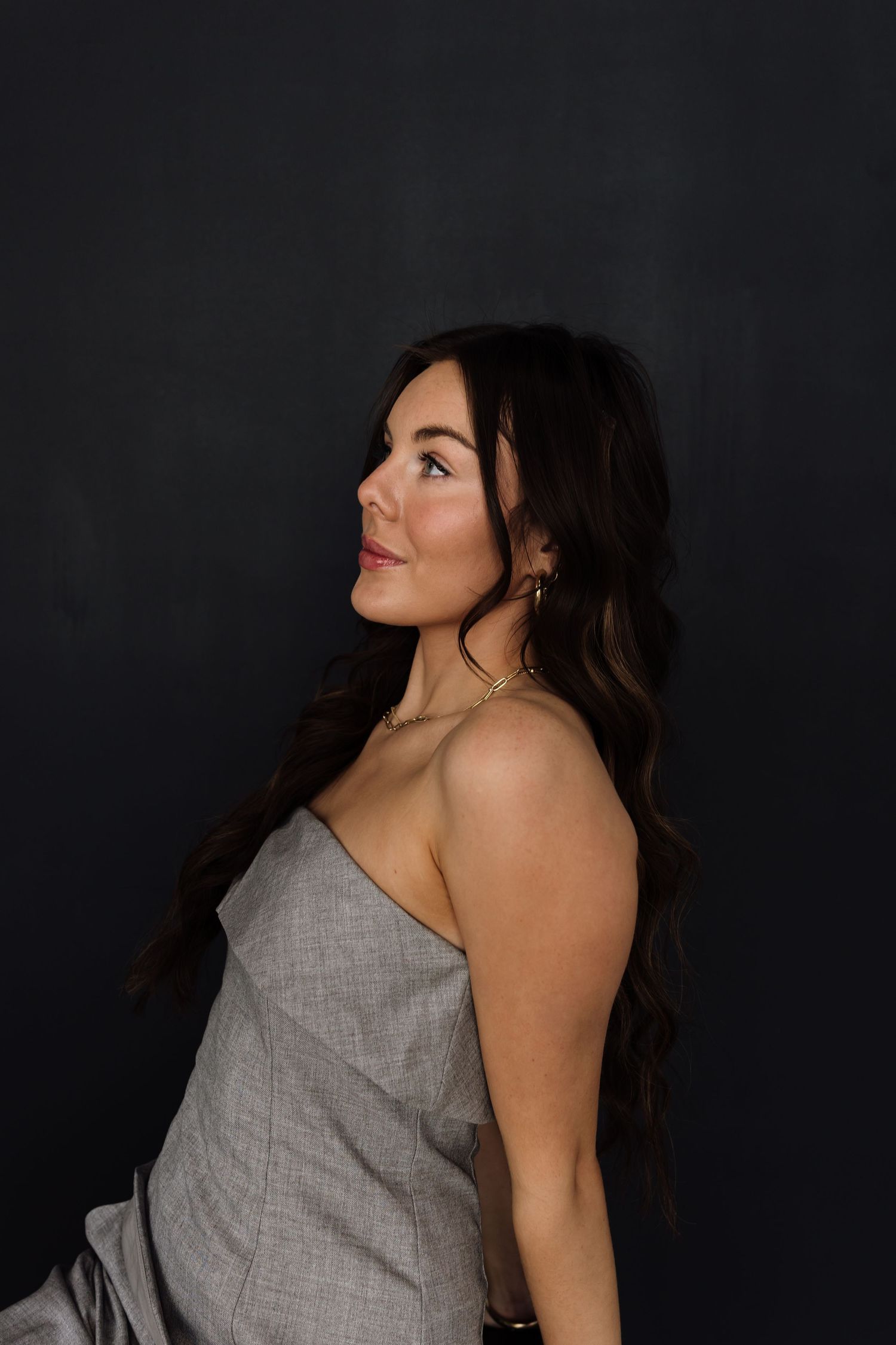 Elegant profile shots in grey sleeveless dress against dark background.