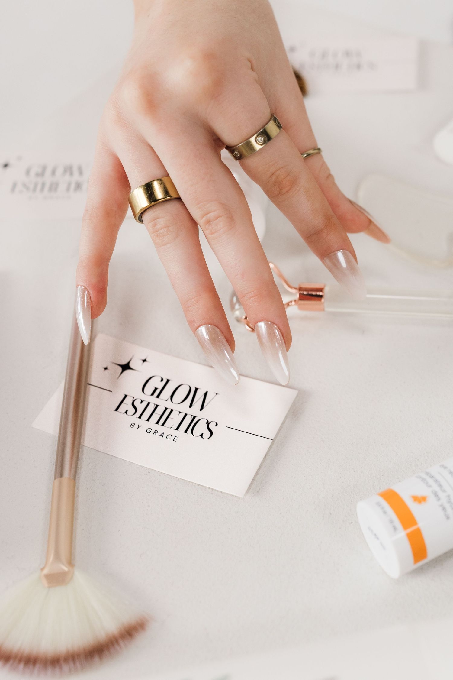 Manicured hands with gold rings arranging beauty product cards.