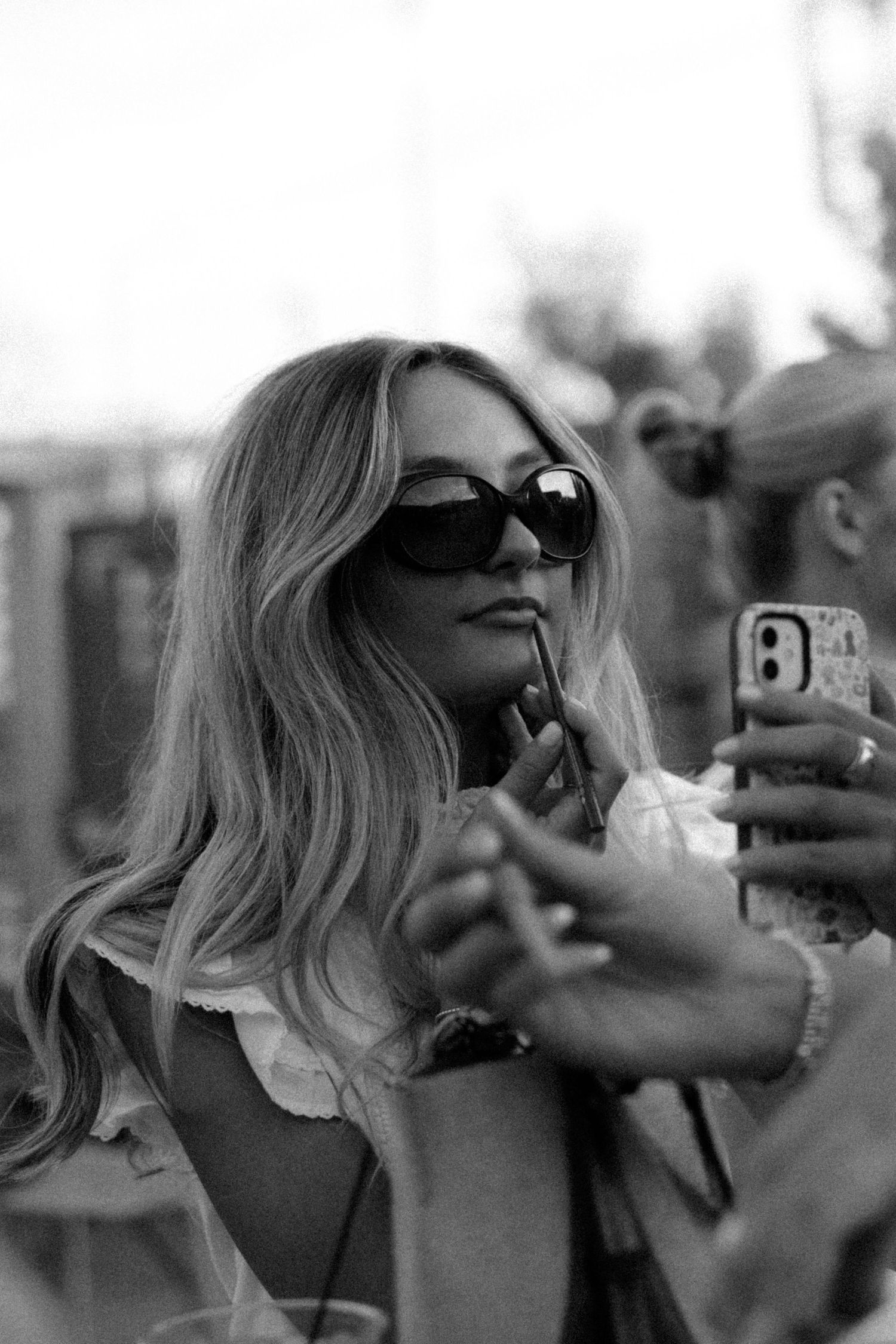 Group taking selfies together outdoors in black and white photography.