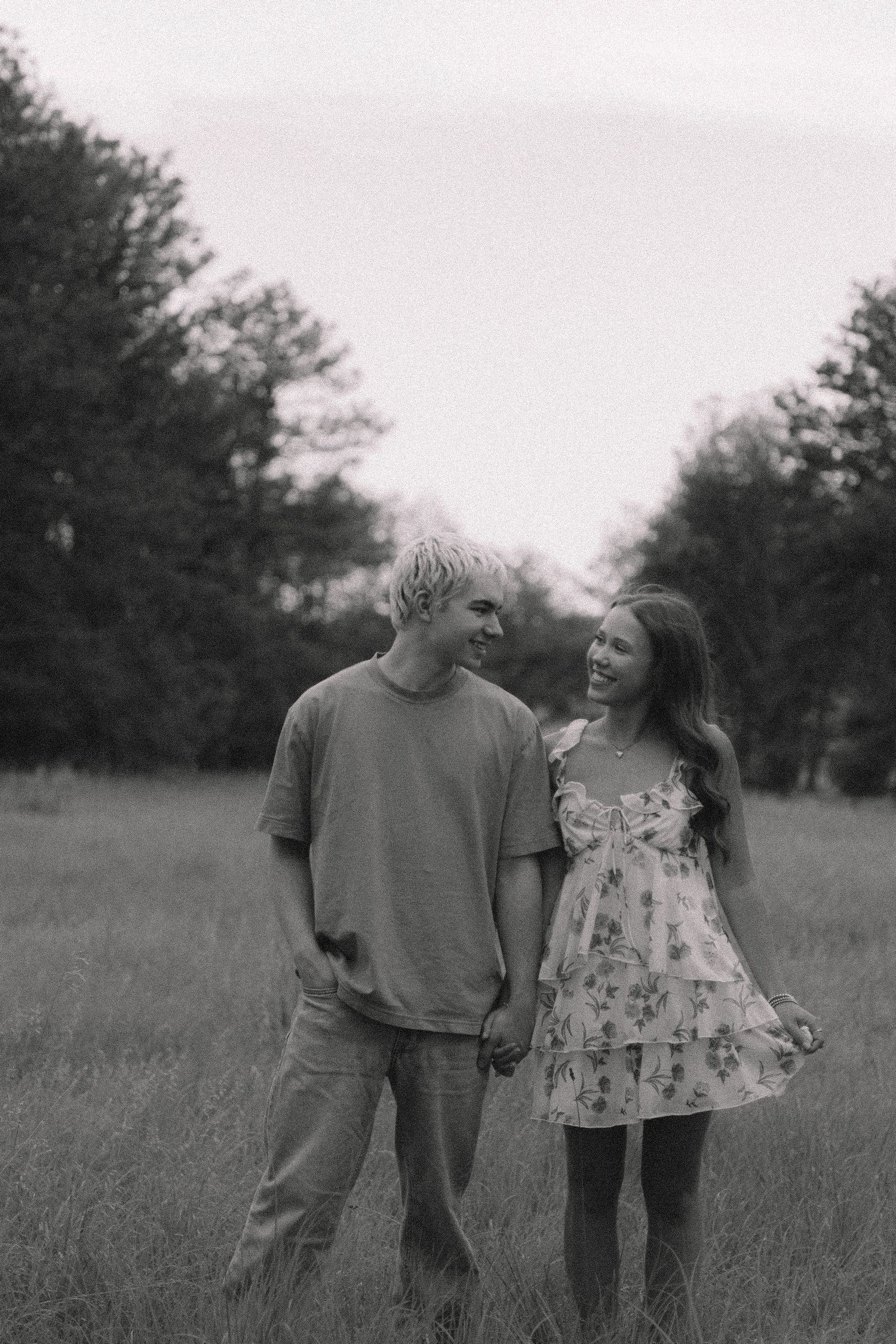 A casual couple shares a tender moment together in a field during sunset.