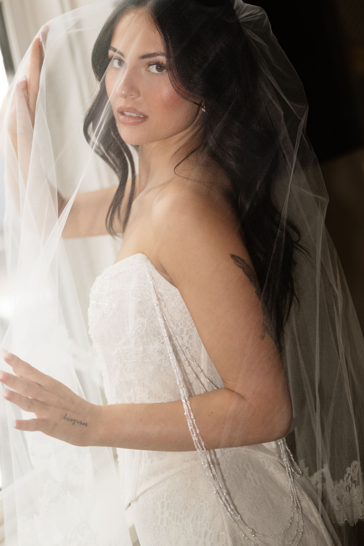 Elegant bridal portrait featuring lace wedding dress and flowing veil.