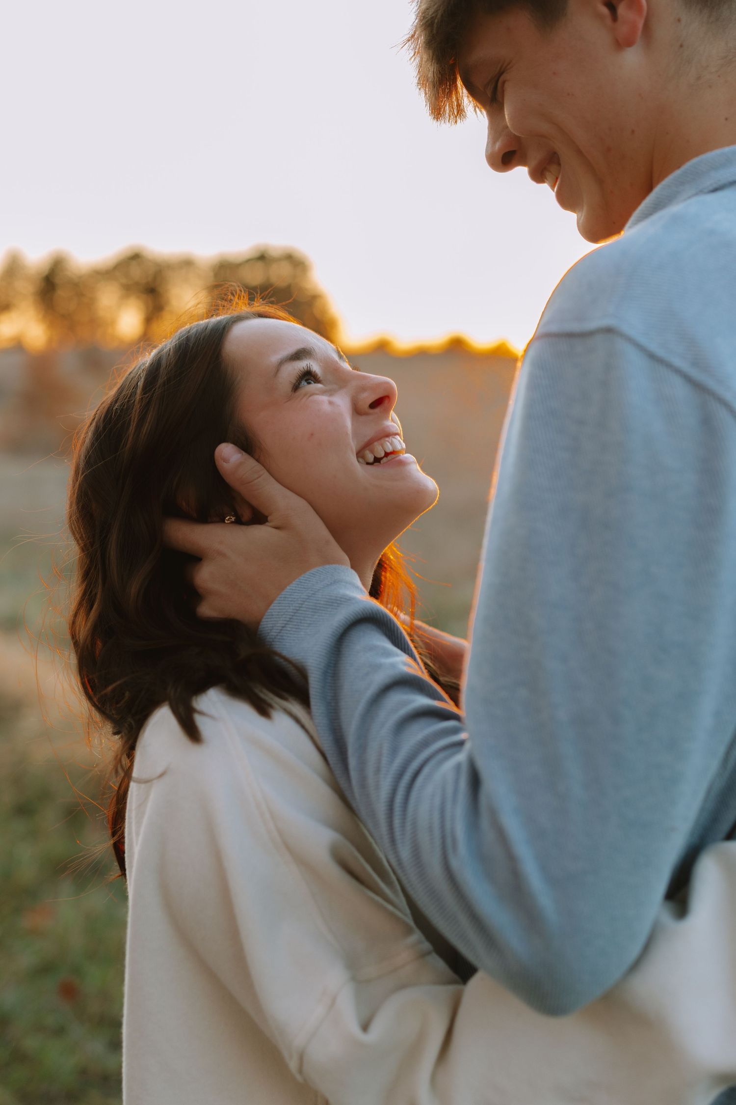 An intimate moment between a couple laughing and embracing during golden hour.
