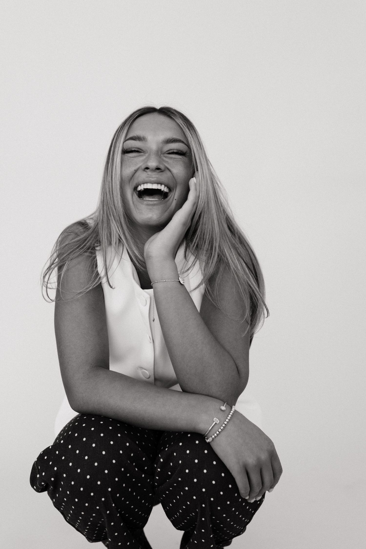 Black and white photo series showing joyful laughter and genuine emotion in polka dot pants against white background.