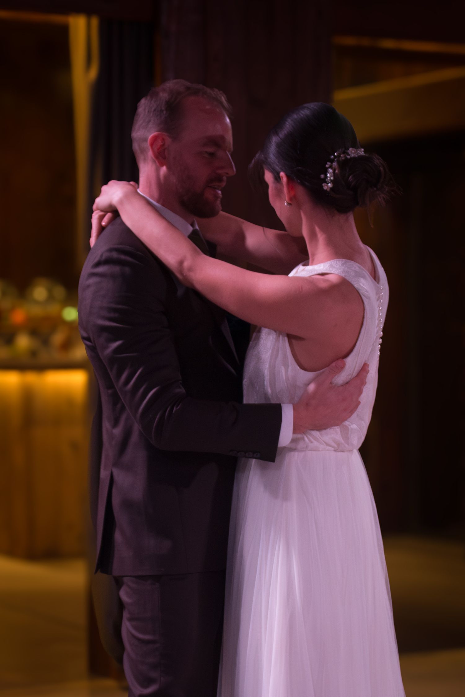 A romantic first dance between newlyweds in a dimly lit reception hall.