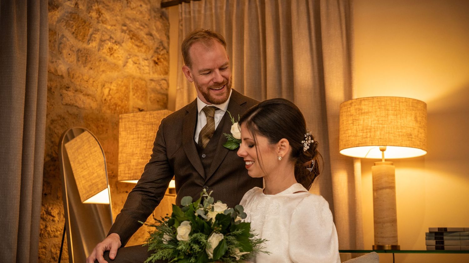 Wedding reception scene with warm lighting and rustic stone wall decor.