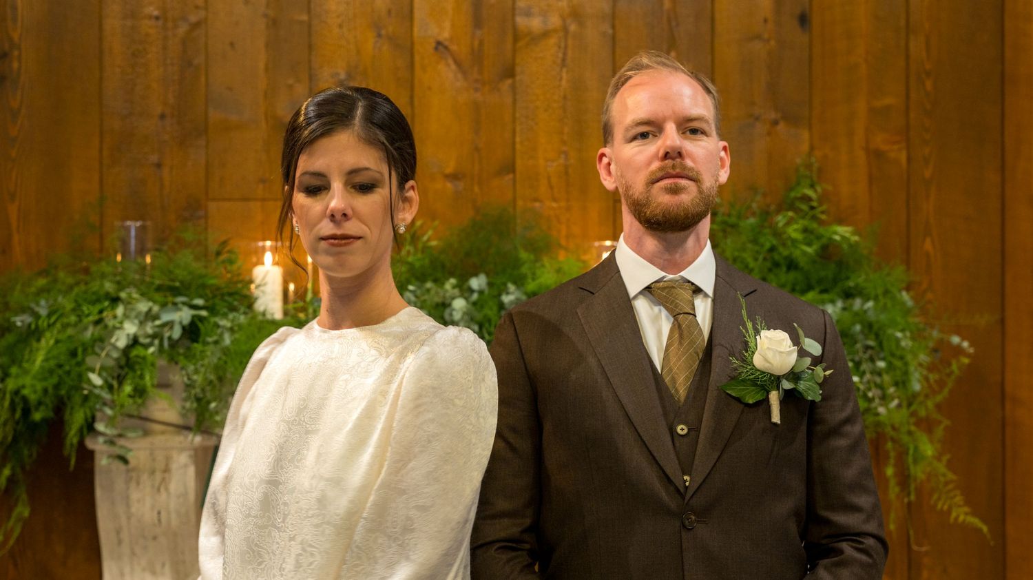 Wedding venue decorated with wooden panels and greenery creating a rustic atmosphere.