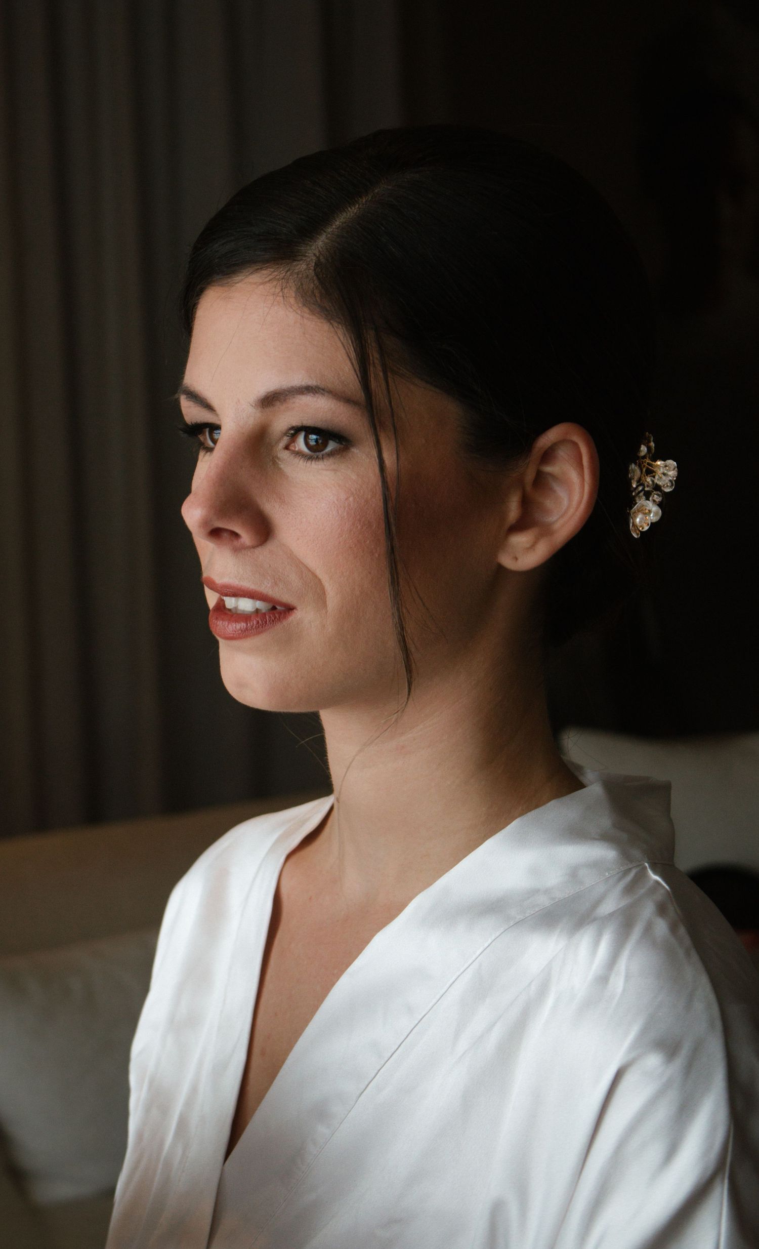Elegant bridal preparation photos showing details of hair and makeup in dramatic lighting.