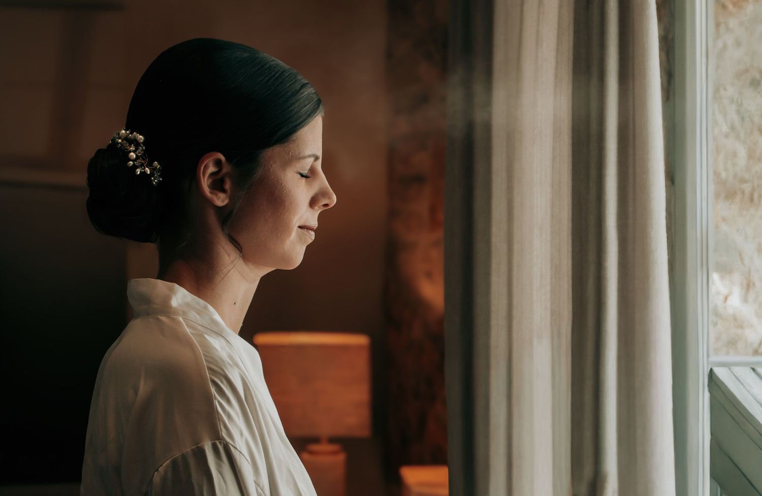Soft window light illuminates a quiet moment during wedding preparations.