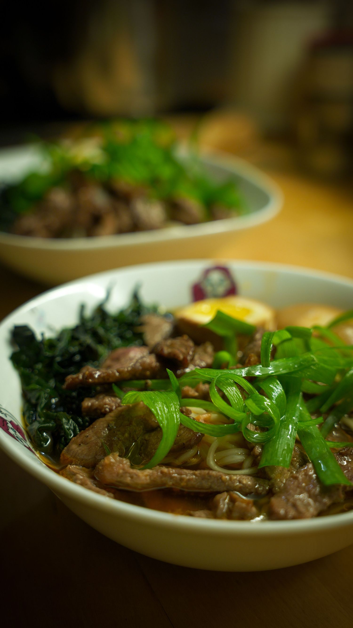 Asian beef stir-fry dish garnished with fresh herbs and greens on white plates.