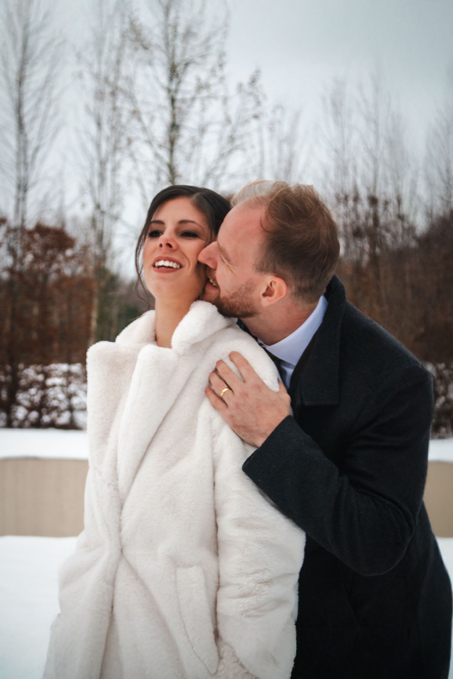 A romantic winter wedding moment captured with the couple in white against a snowy landscape.